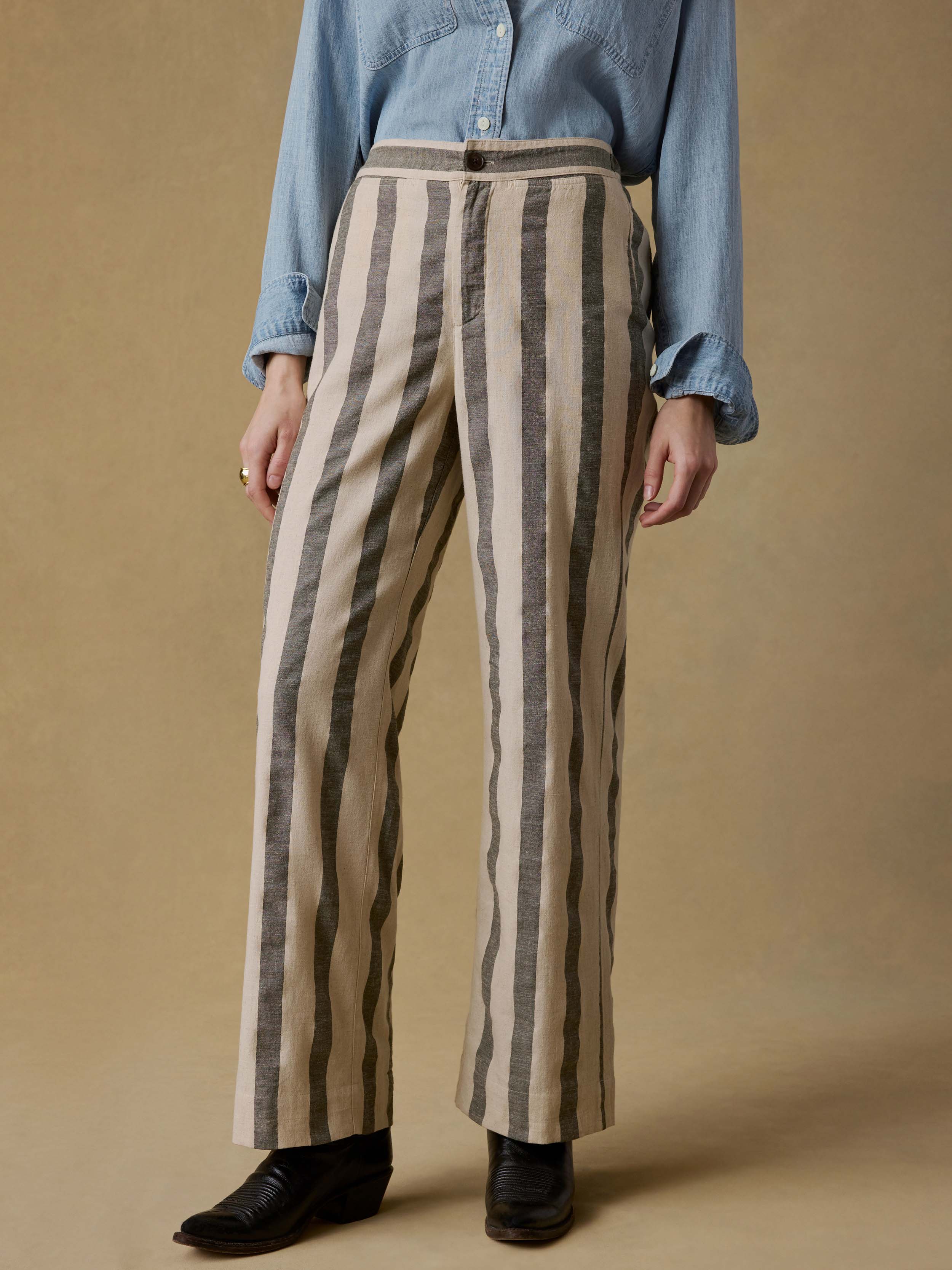 Woman wearing a blue shirt and green striped pants against a beige background