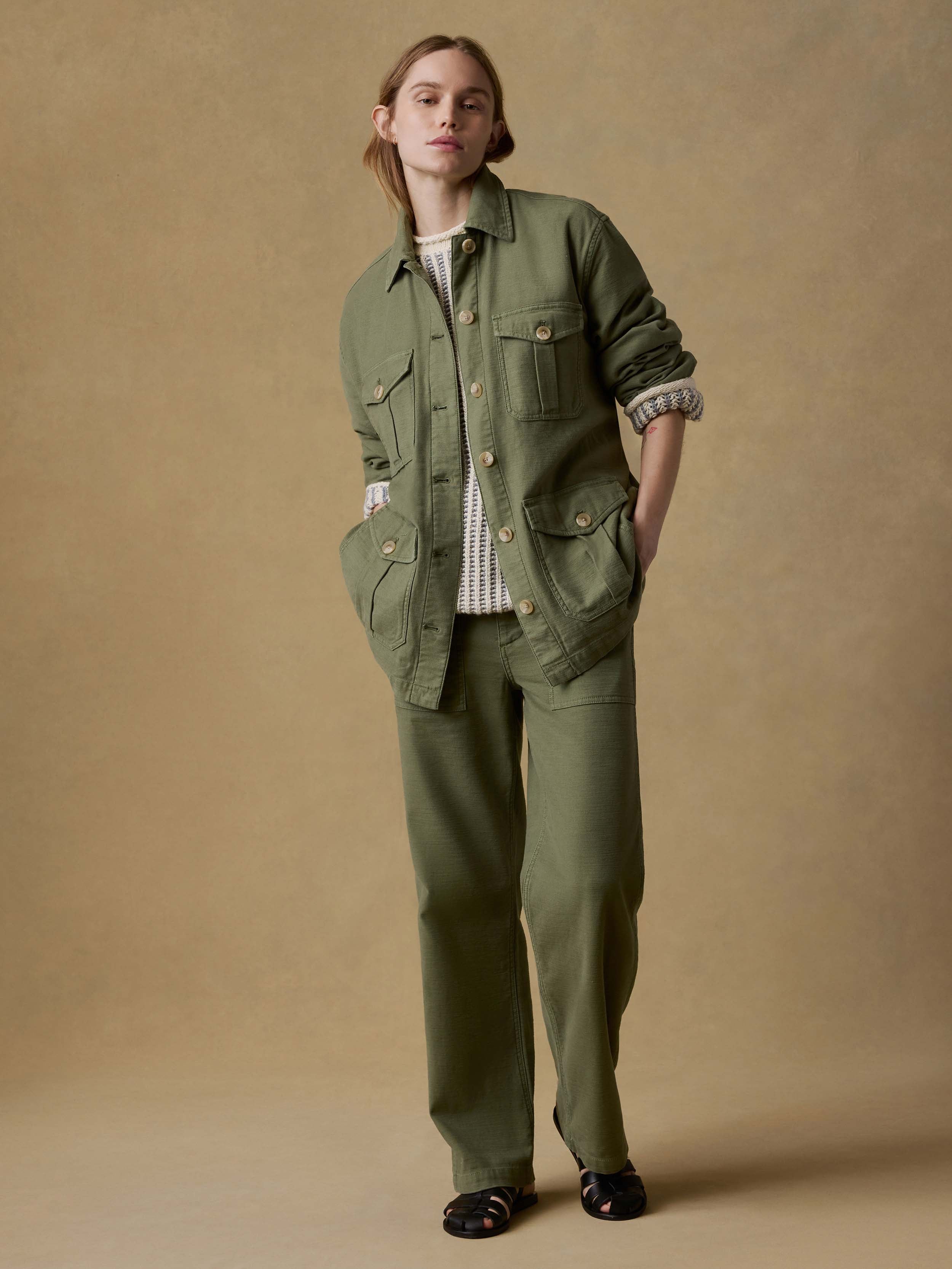 Woman wearing a green jacket and pants against a beige background