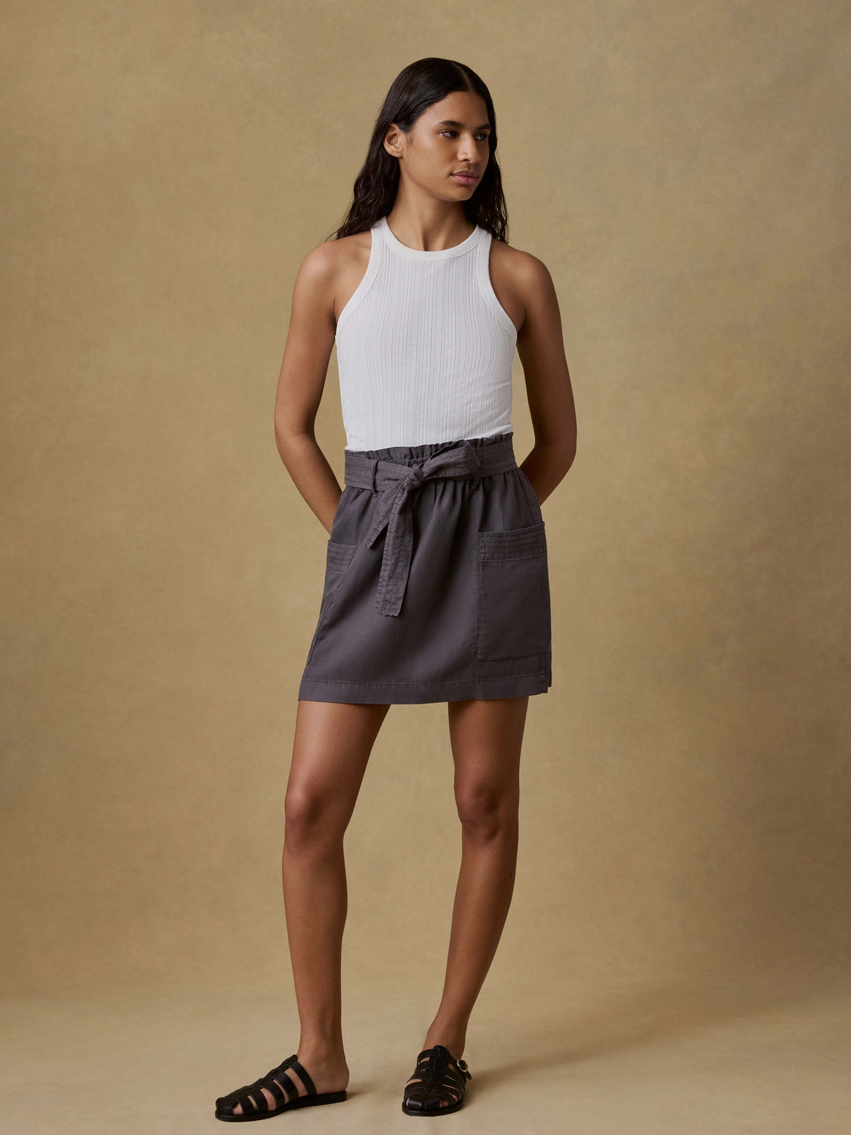 A woman wearing a black skirt and white tank top, image 3 of 4