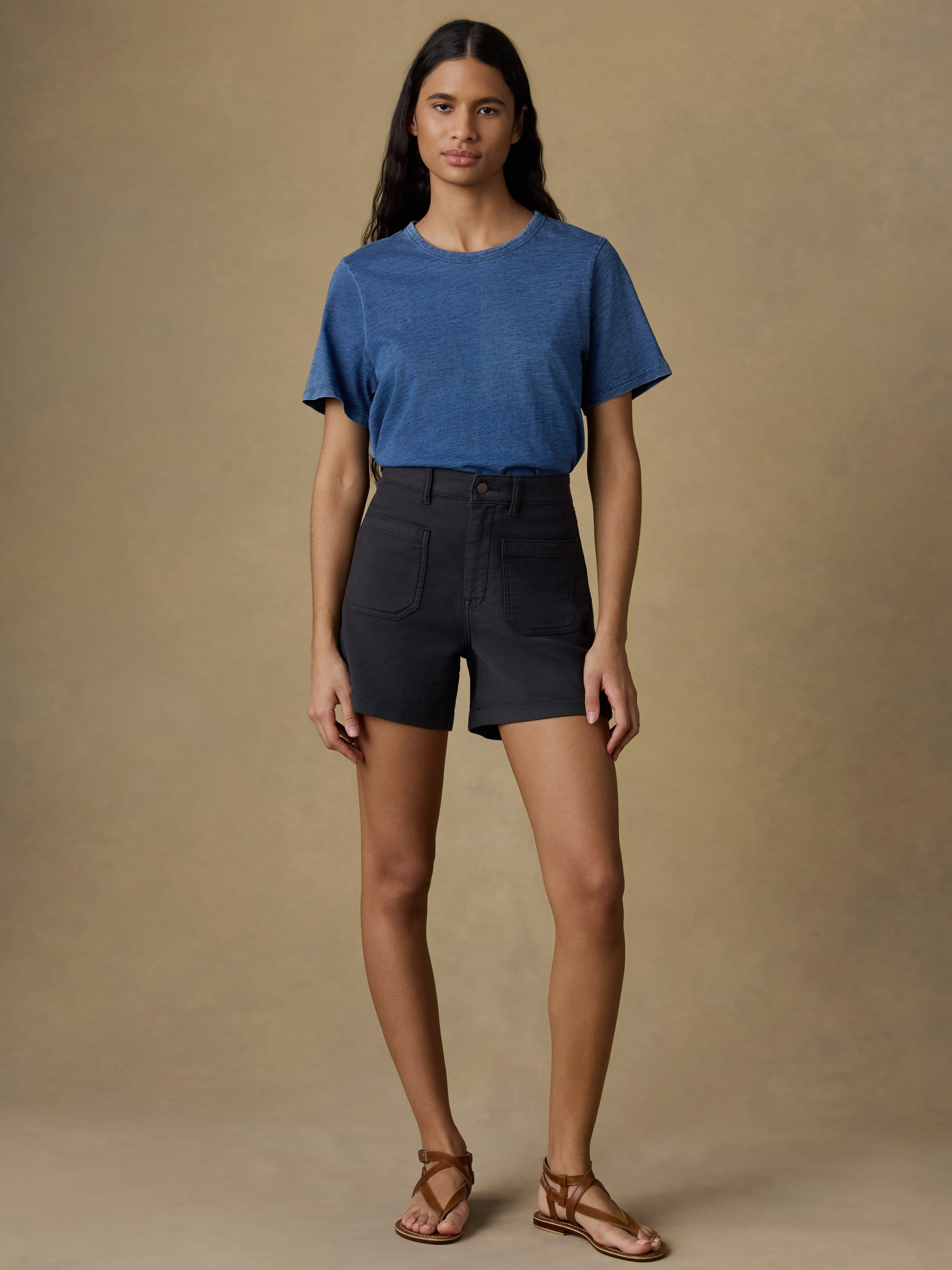 Woman wearing a blue t-shirt and black shorts against a beige background