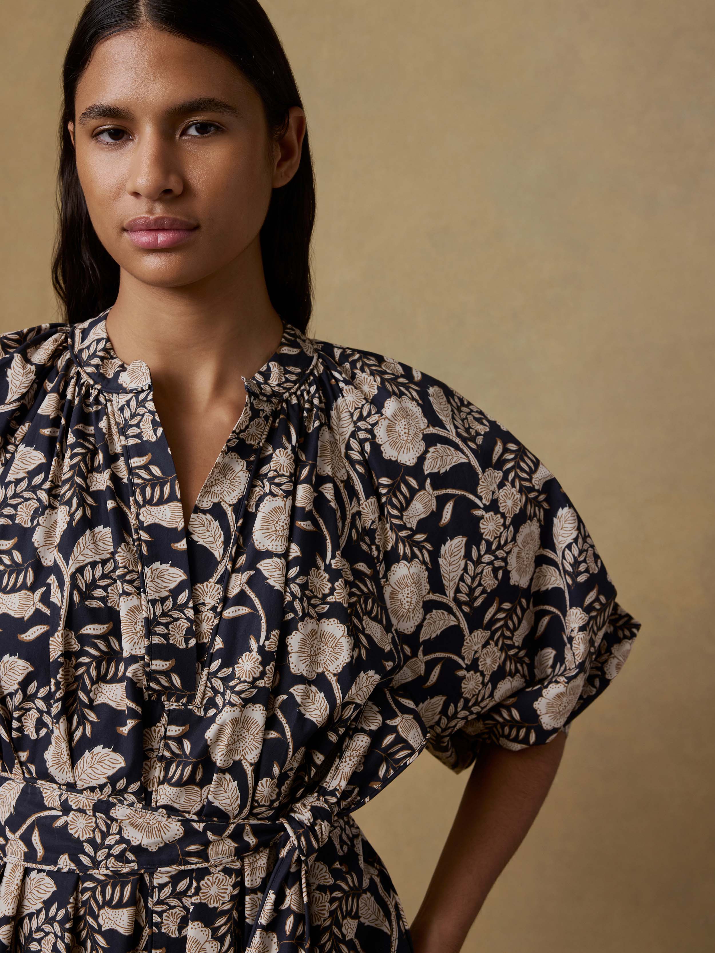 Woman wearing a floral dress against a beige background
