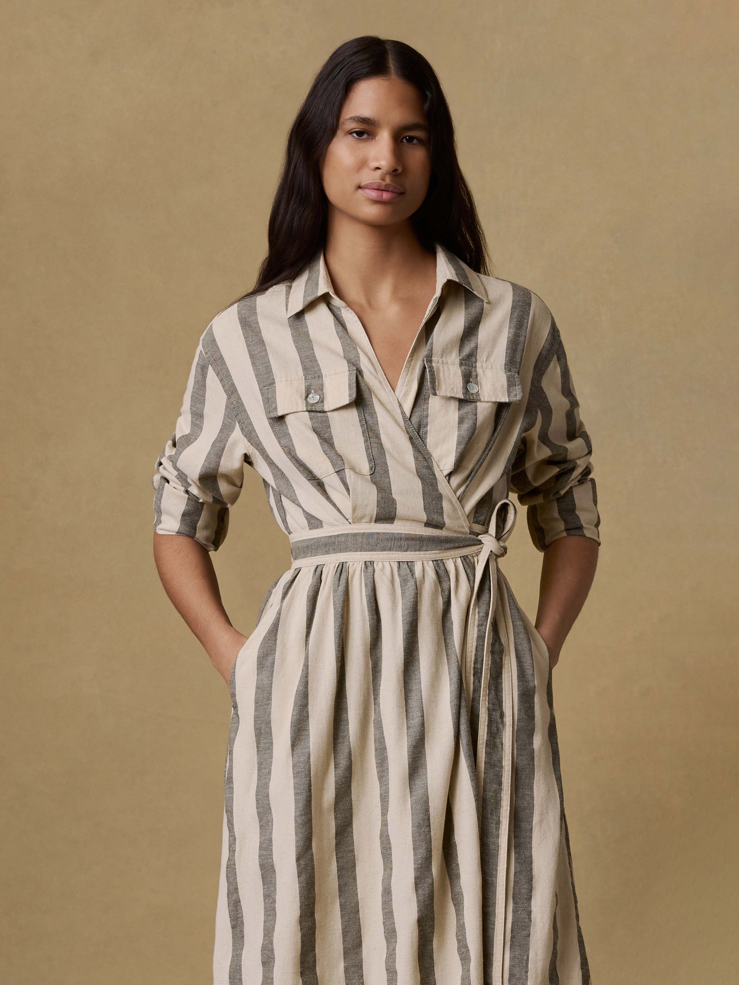 Woman wearing a green and white striped wrap dress against a beige background