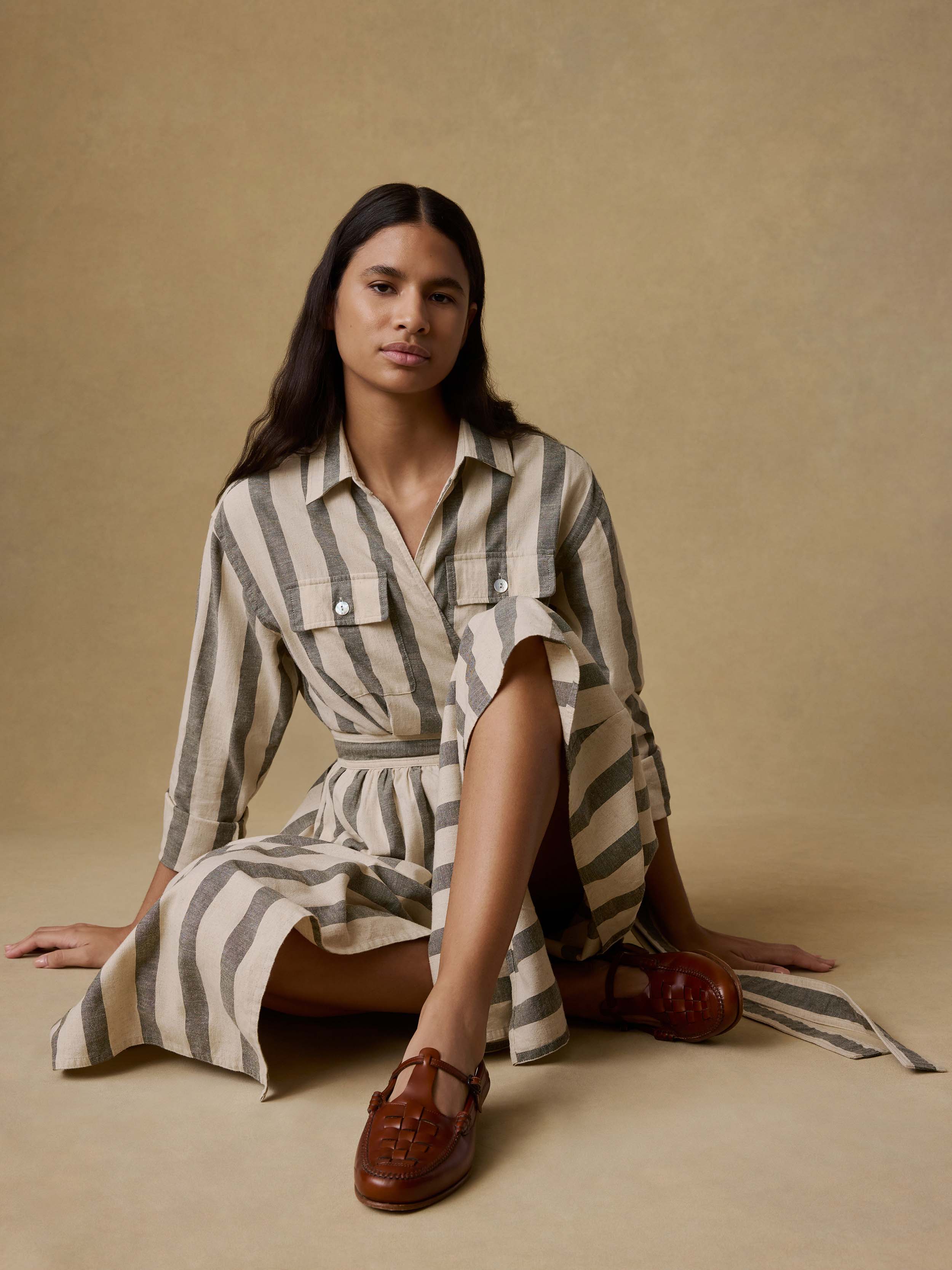 Woman wearing a green and white striped wrap dress against a beige background