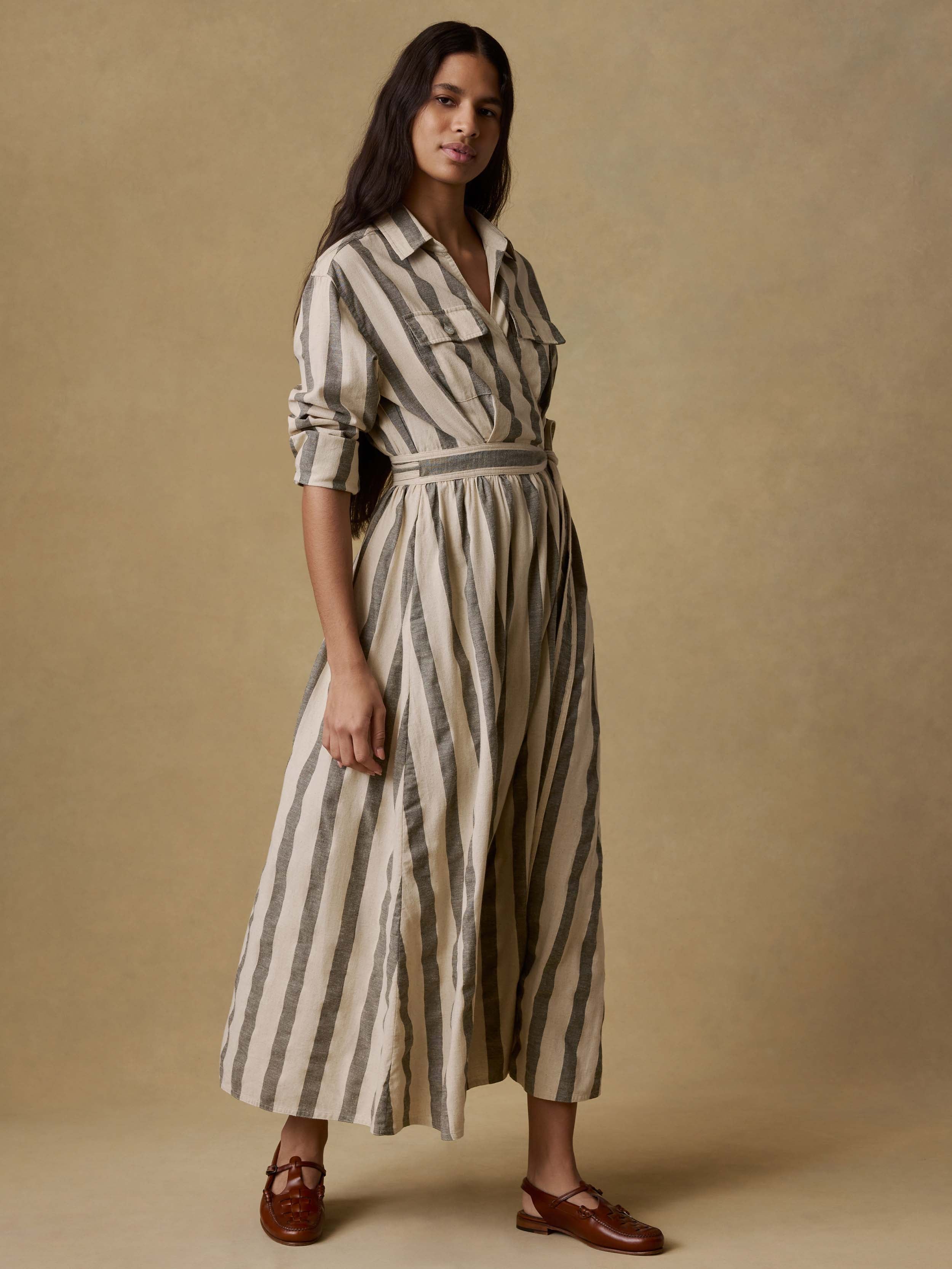 Woman wearing a green and white striped wrap dress against a beige background