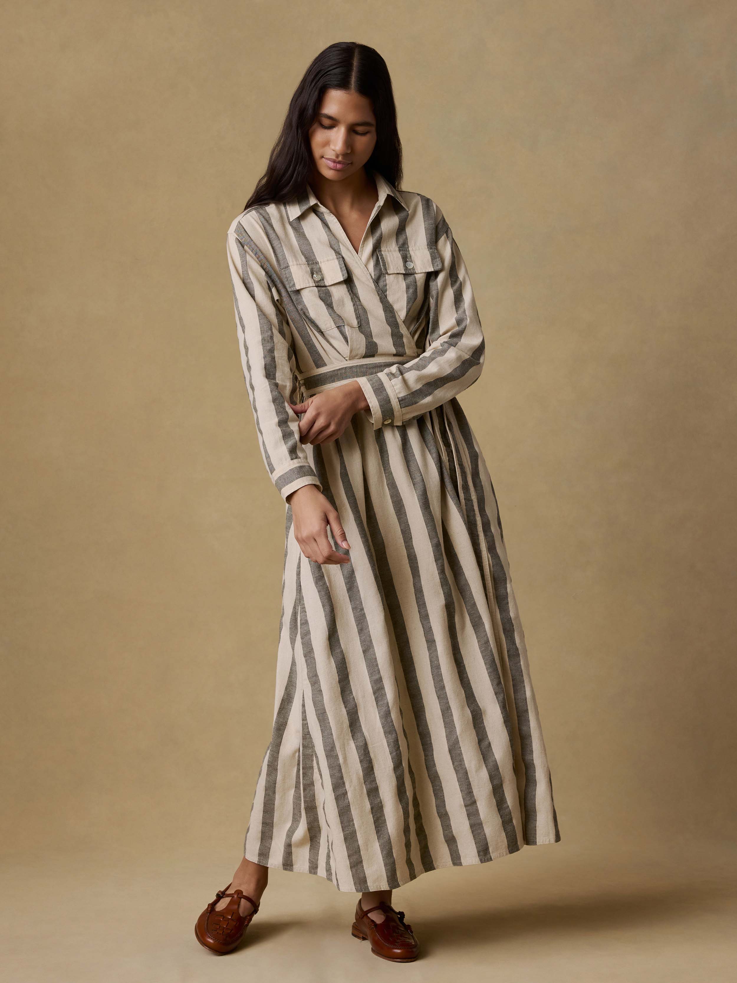 Woman wearing a green and white striped wrap dress against a beige background