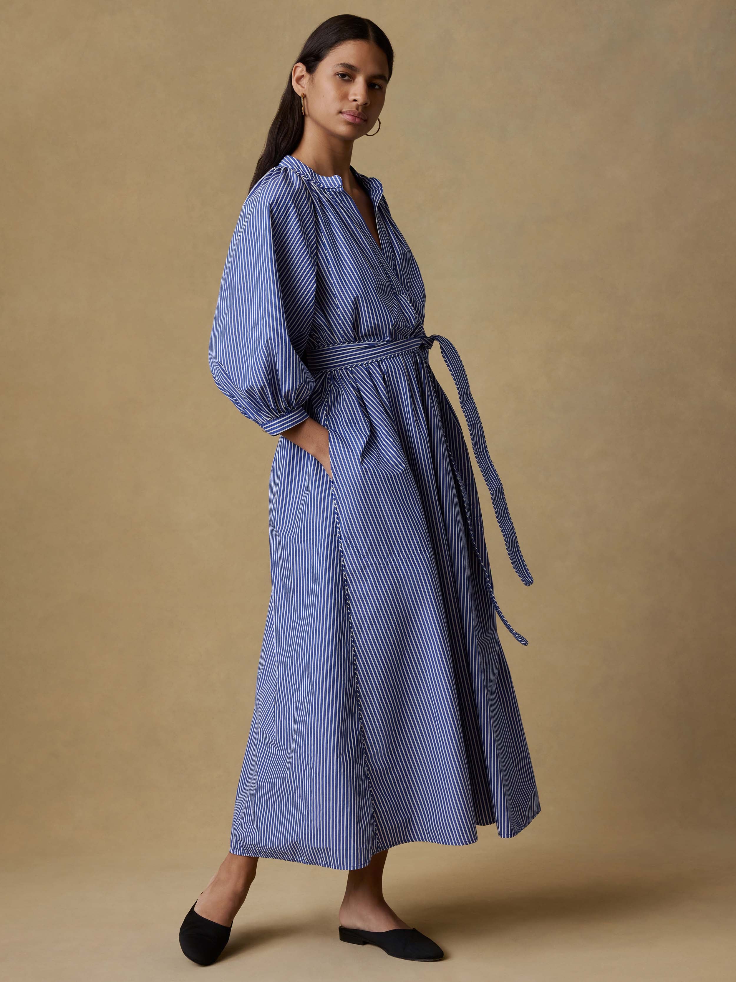 Woman wearing a blue striped dress against a beige background