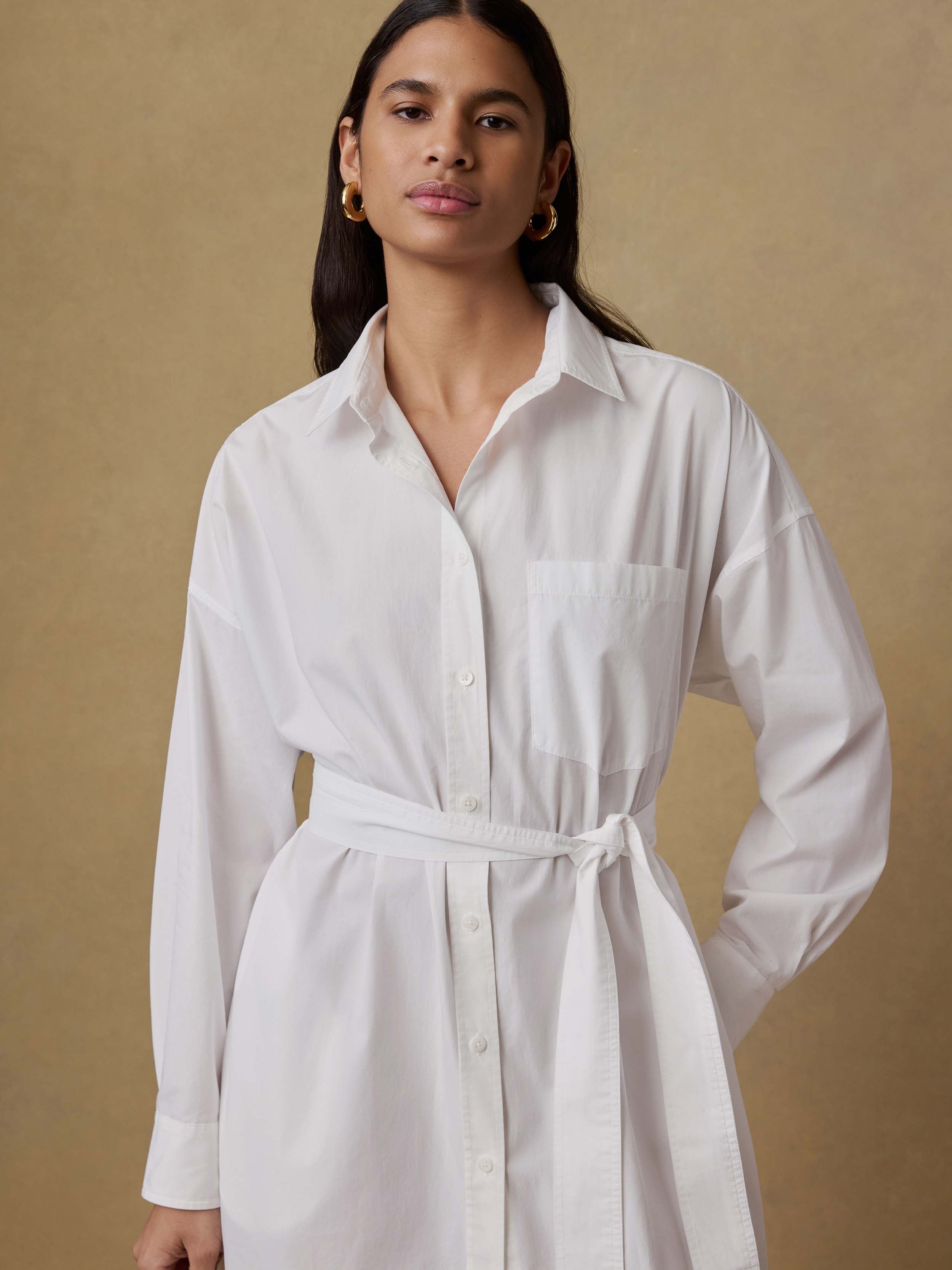 Woman wearing a white dress against a beige background