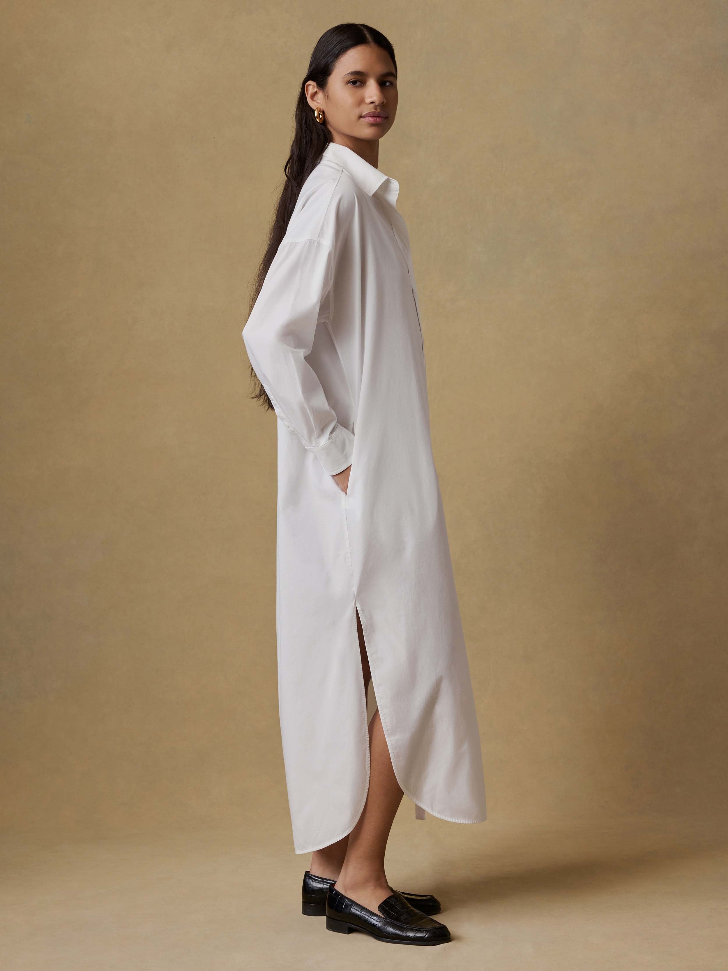 Woman wearing a long white dress against a beige background