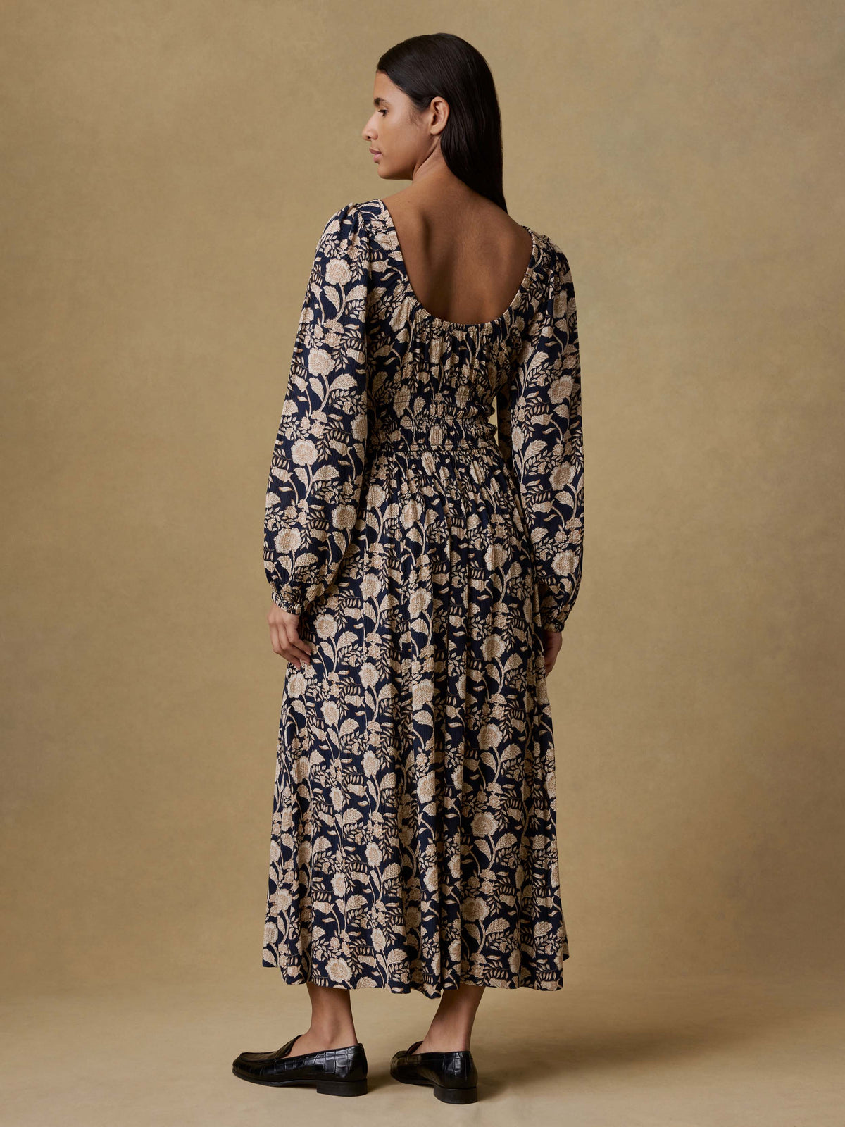 A woman viewed from behind wearing a floral printed dress and loafers, image 4 of 5