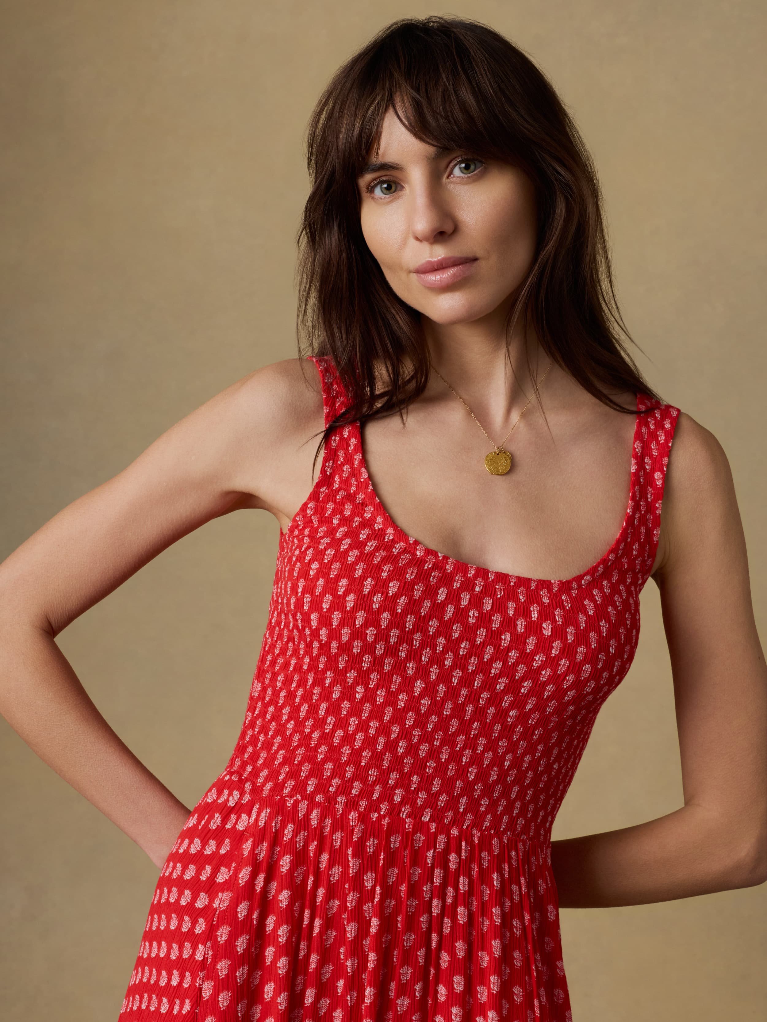 Close up of a woman wearing a red floral patterned dress against a beige background