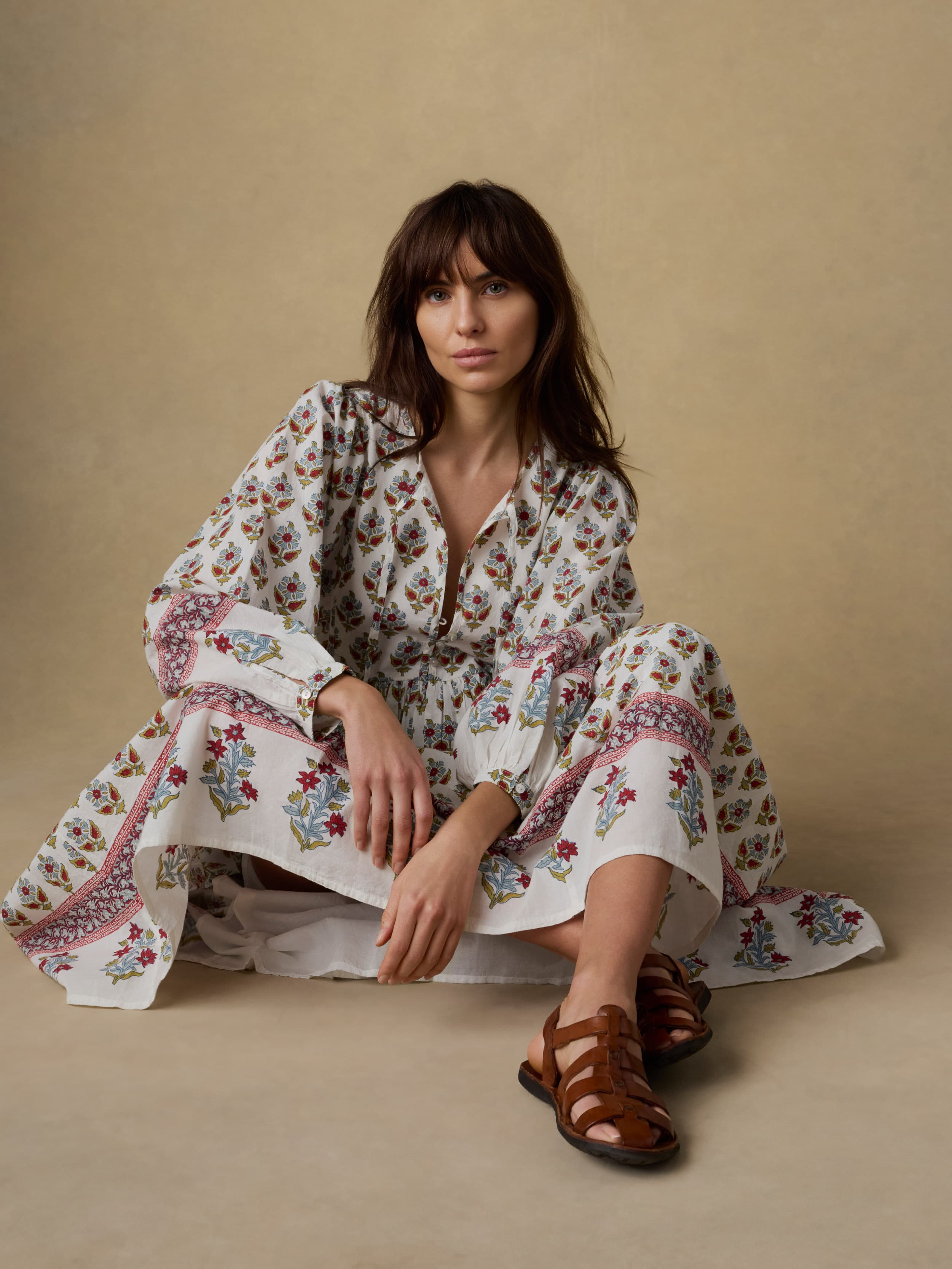 Woman wearing a long floral dress against a beige background