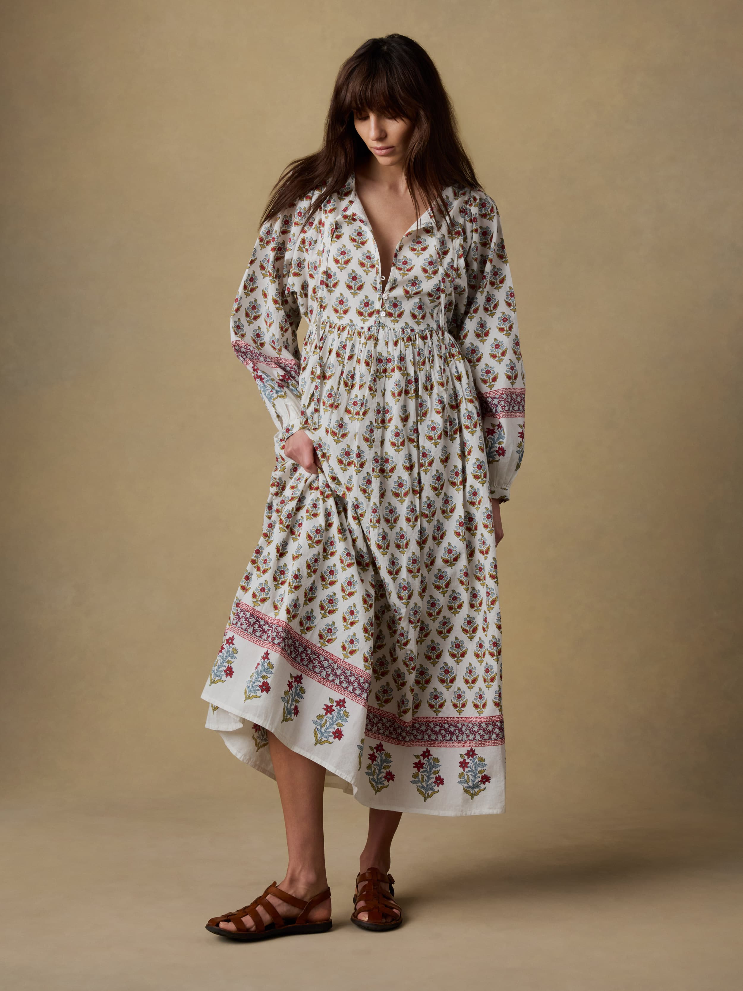 Woman wearing a long floral dress against a beige background