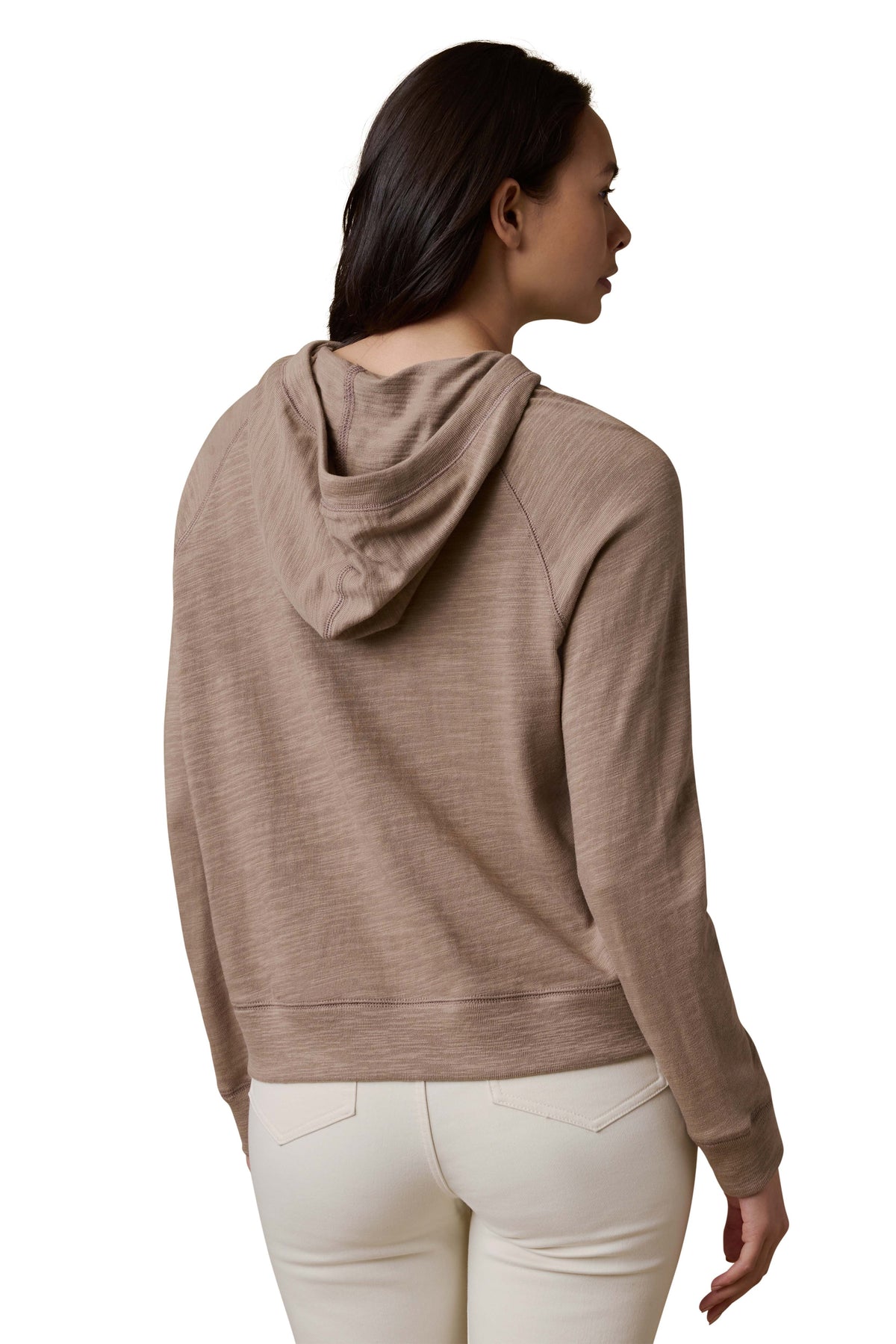 A woman viewed from behind wearing a beige hoodie and white pants, image 3 of 3
