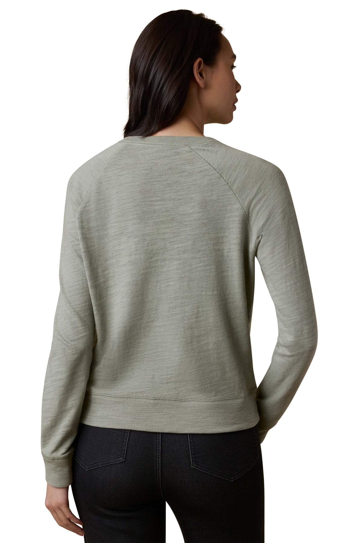 A woman viewed from the back wearing a sage green crewneck and dark jeans, image 3 of 3