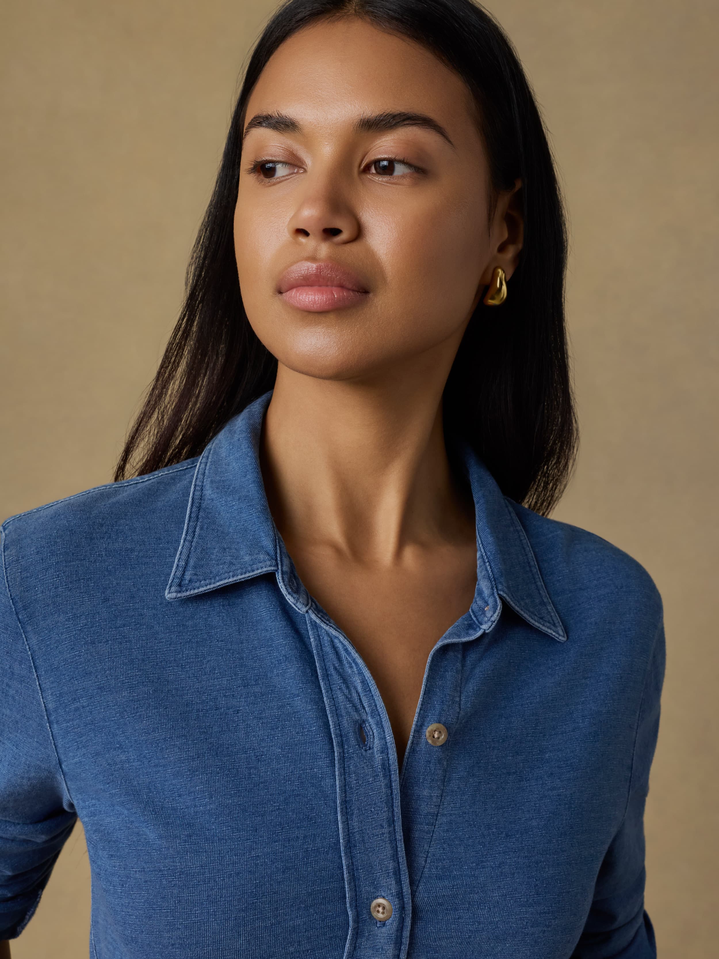 Woman wearing a blue knit shirt against a beige background