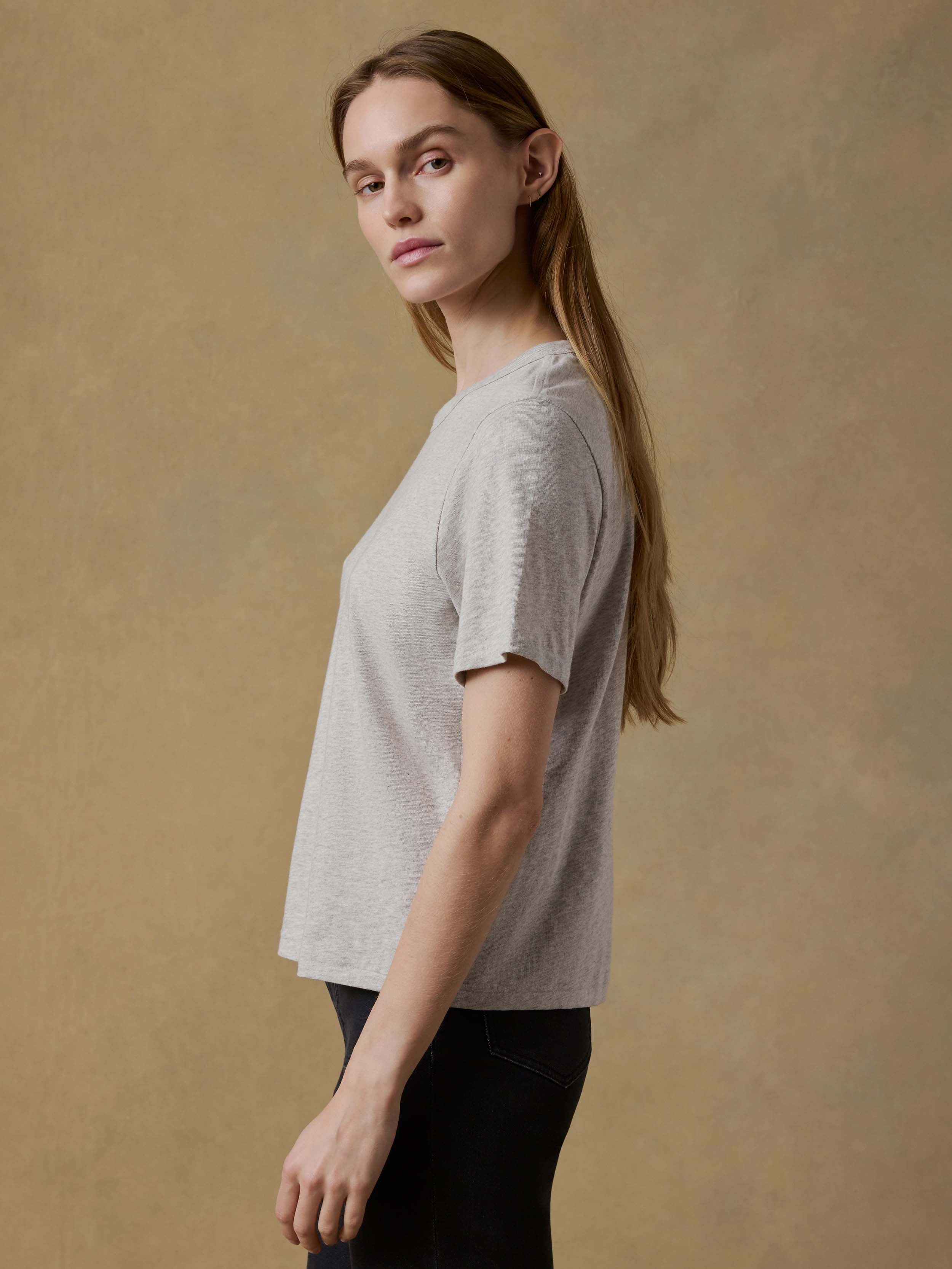 Woman wearing a gray t-shirt and black pants against a beige background