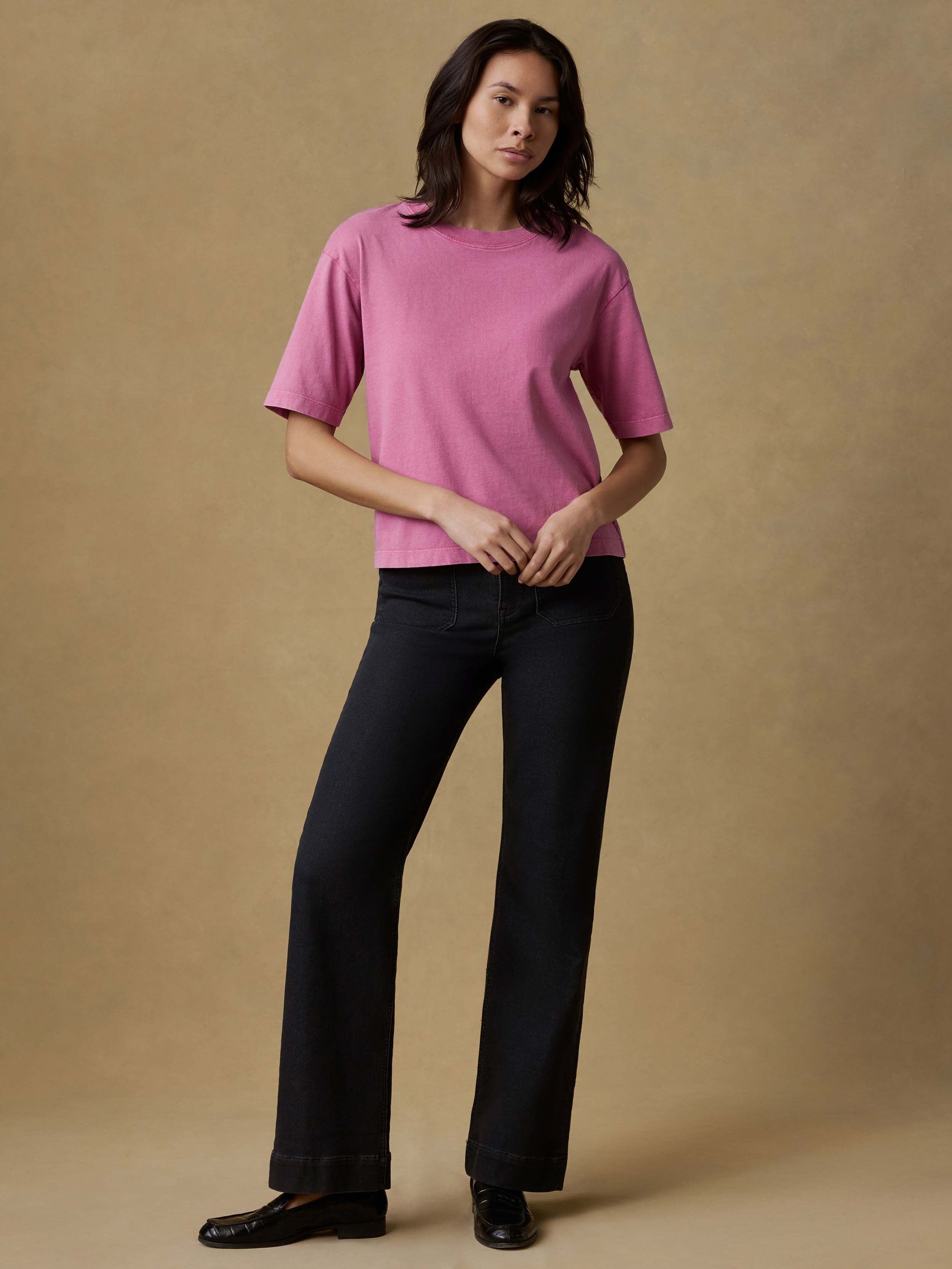 Woman wearing a pink t-shirt and black stretch terry pants against a beige background
