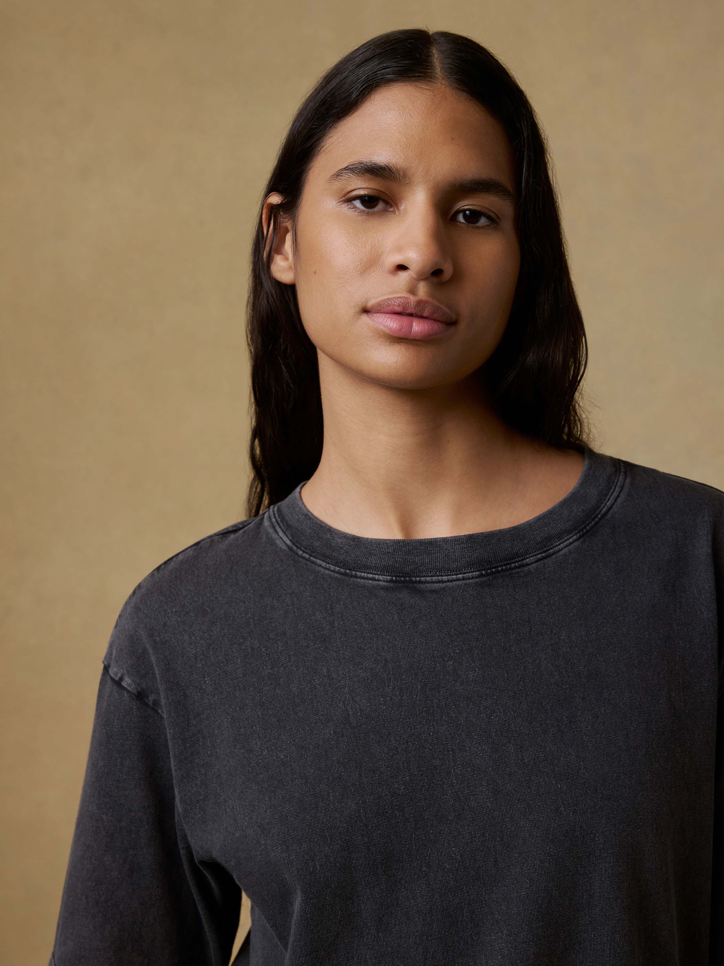 Woman wearing a black t-shirt against a brown background