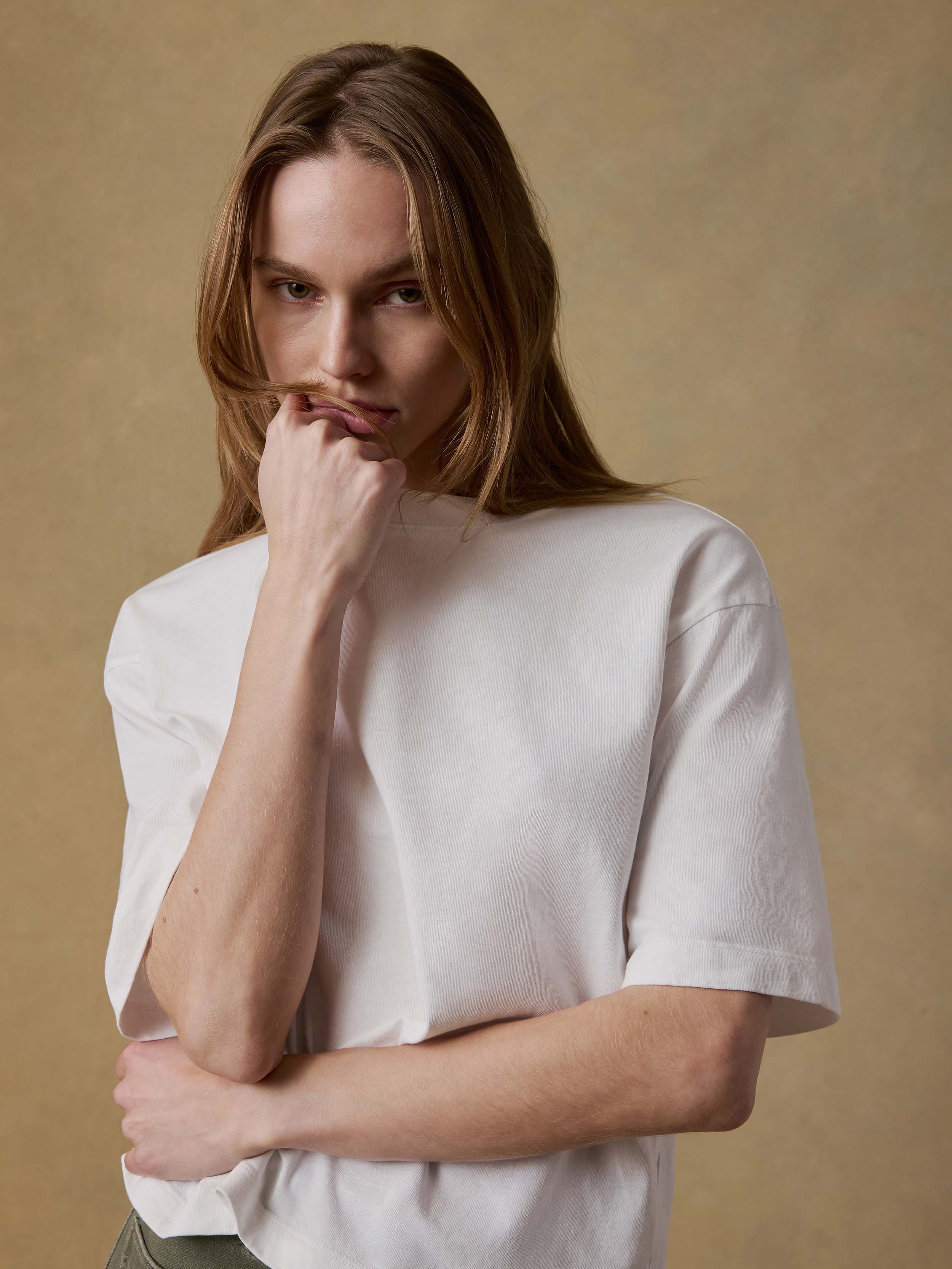Woman wearing a white t-shirt and green pants against a beige background