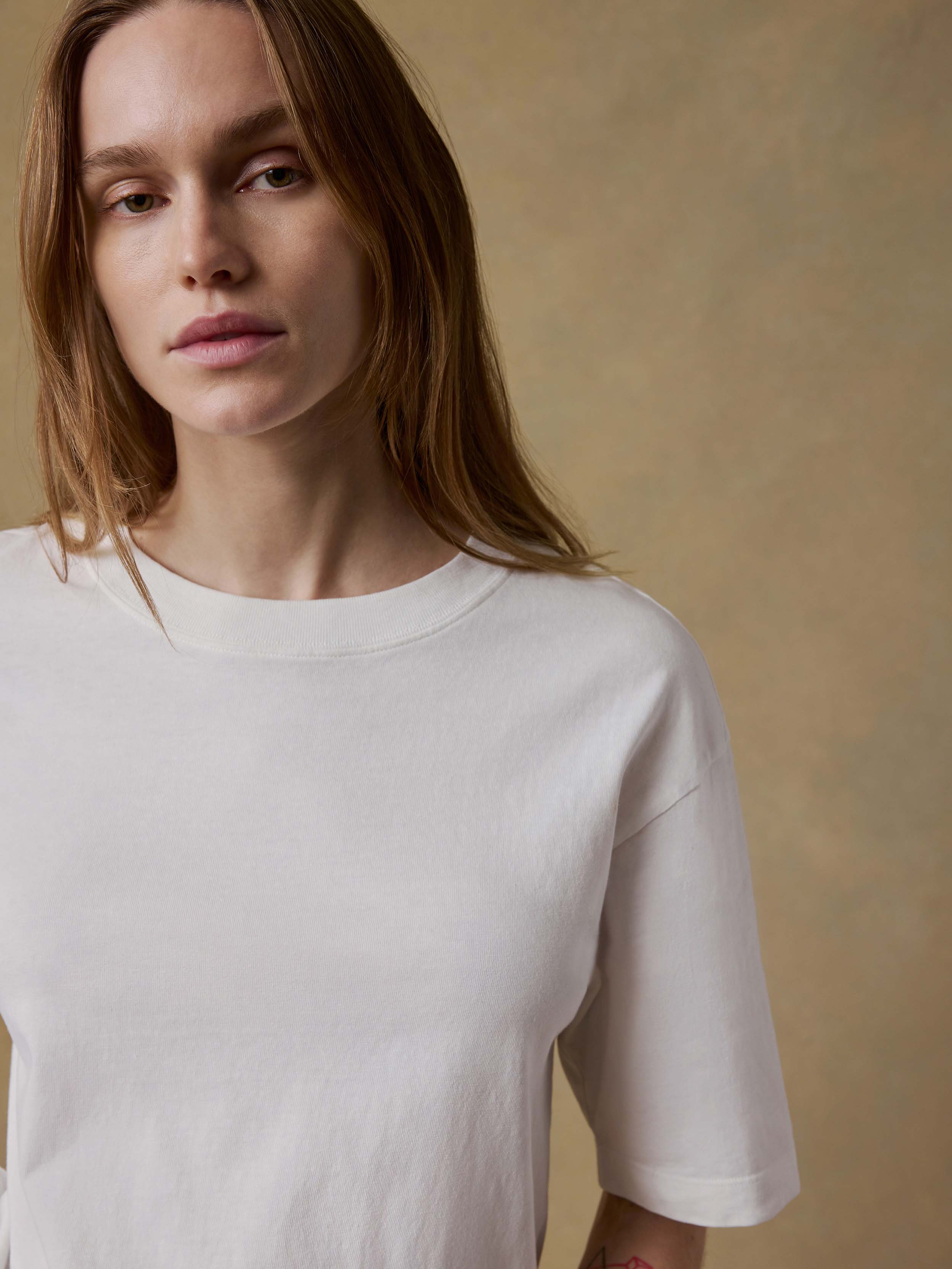 Woman wearing a white t-shirt against a beige background