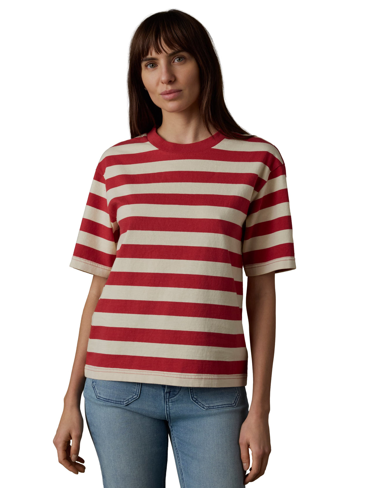 A woman wearing a red and white short sleeve tee and blue jeans, image 1 of 3