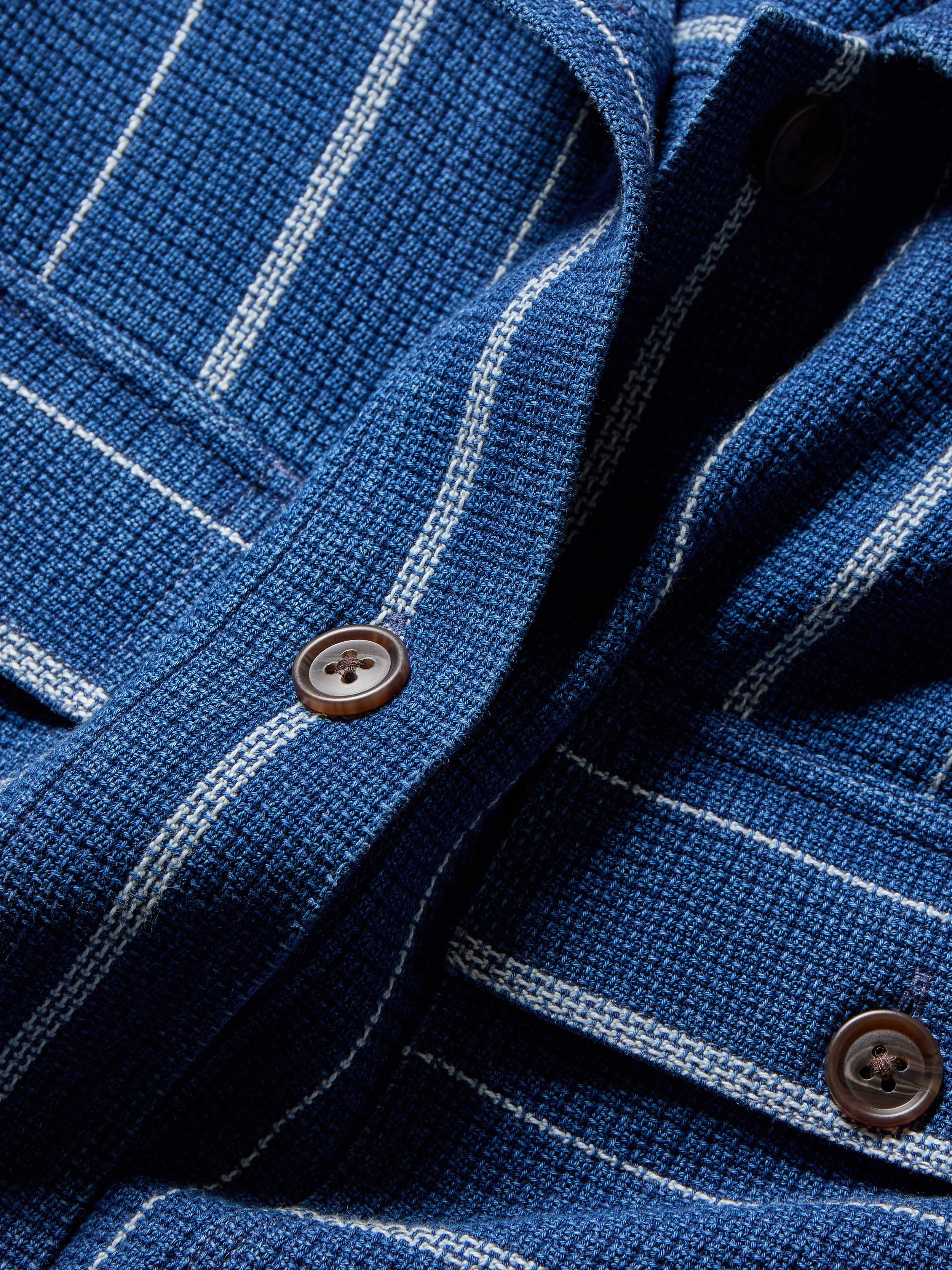 Close-up of a blue textured jacket with white pinstripes and brown buttons.