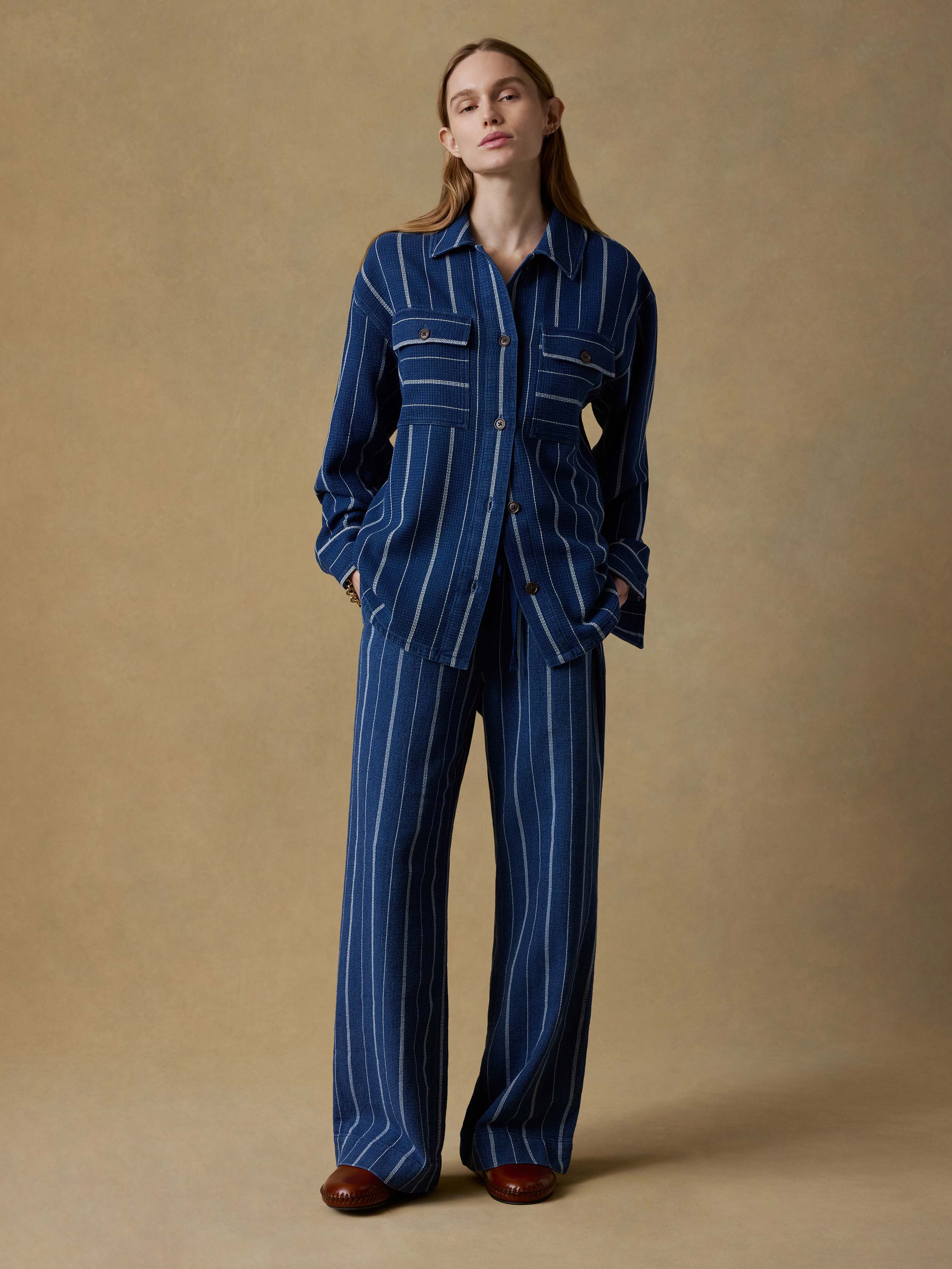 Woman wearing a blue striped top and matching bottom against a beige background
