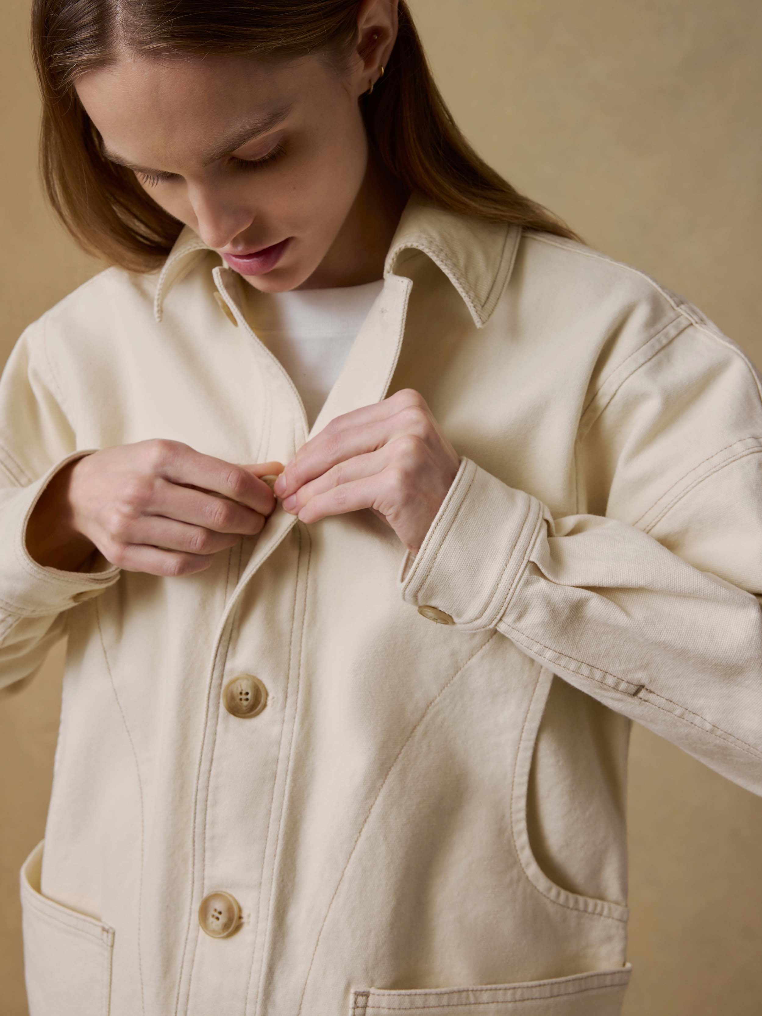 Woman wearing a light-colored jacket against a beige background