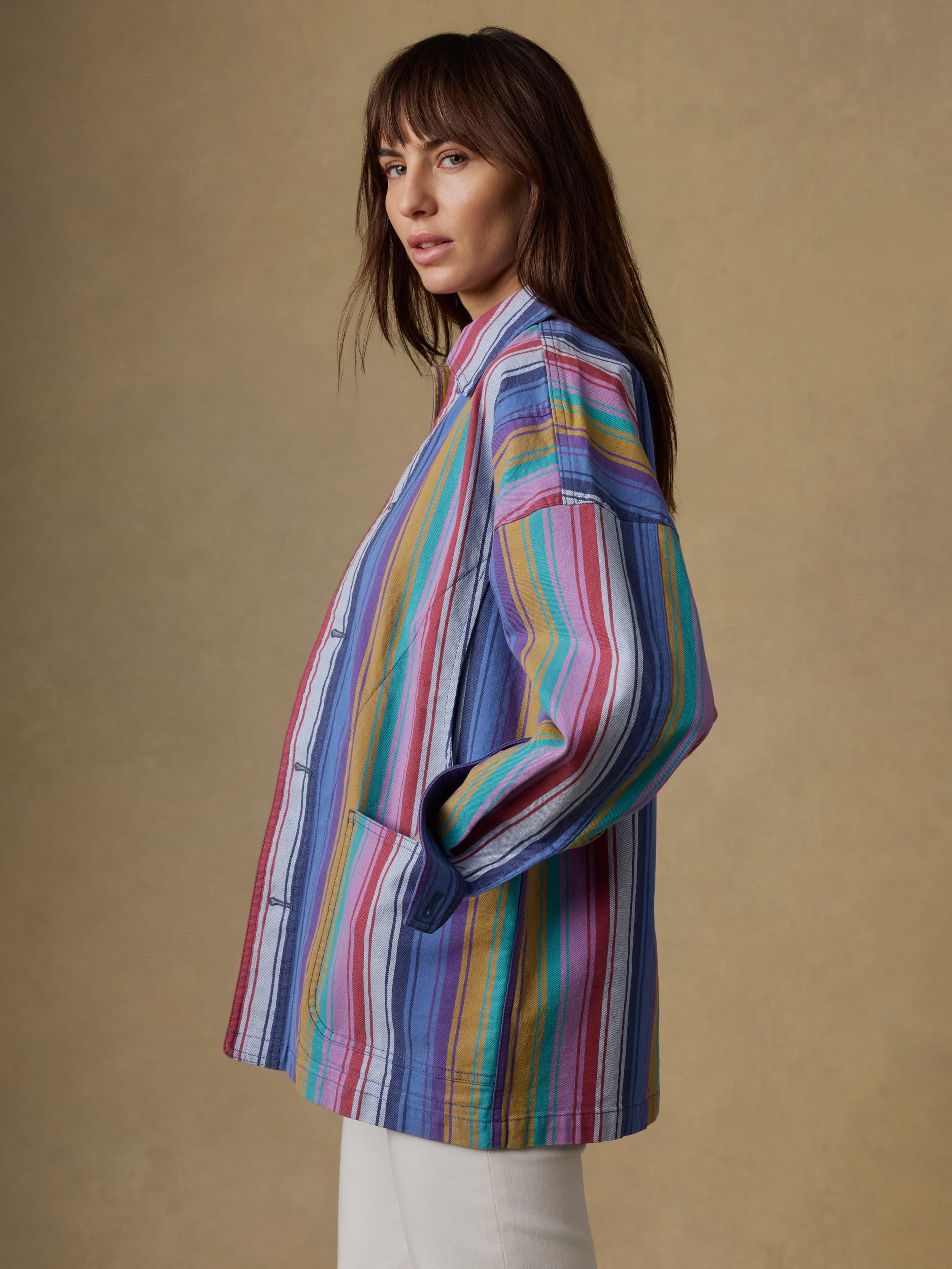 Woman wearing a colorful striped jacket against a beige background