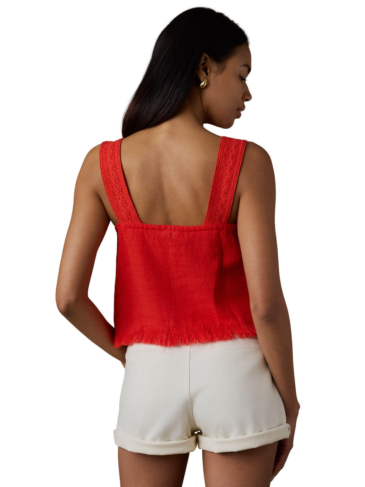 A woman viewed from behind wearing a red tank top and white shorts, image 3 of 5