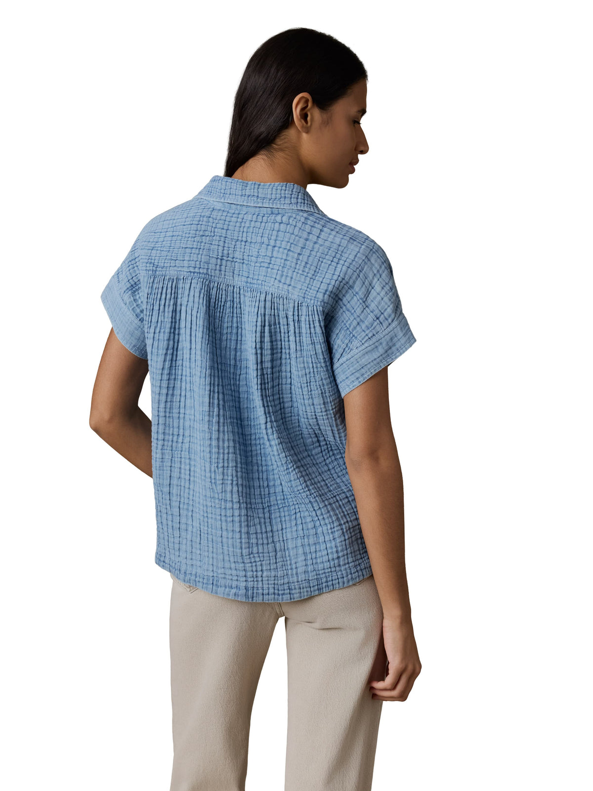A woman viewed from behind wearing a blue gauze top and beige pants, image 3 of 3