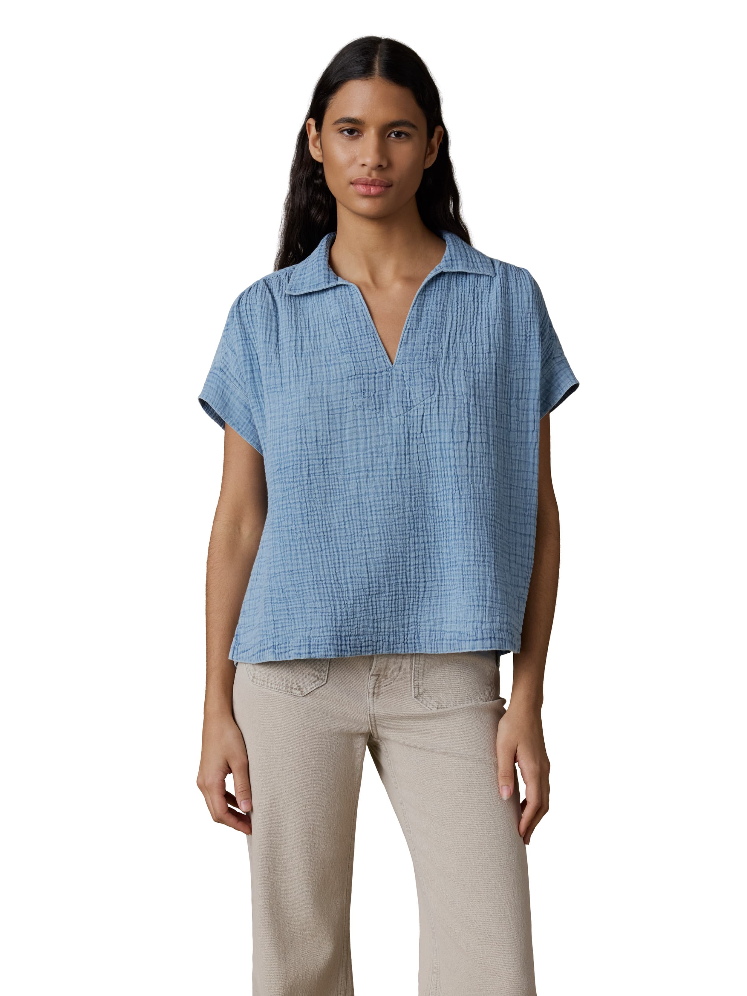 A woman wearing a blue gauze top and beige pants