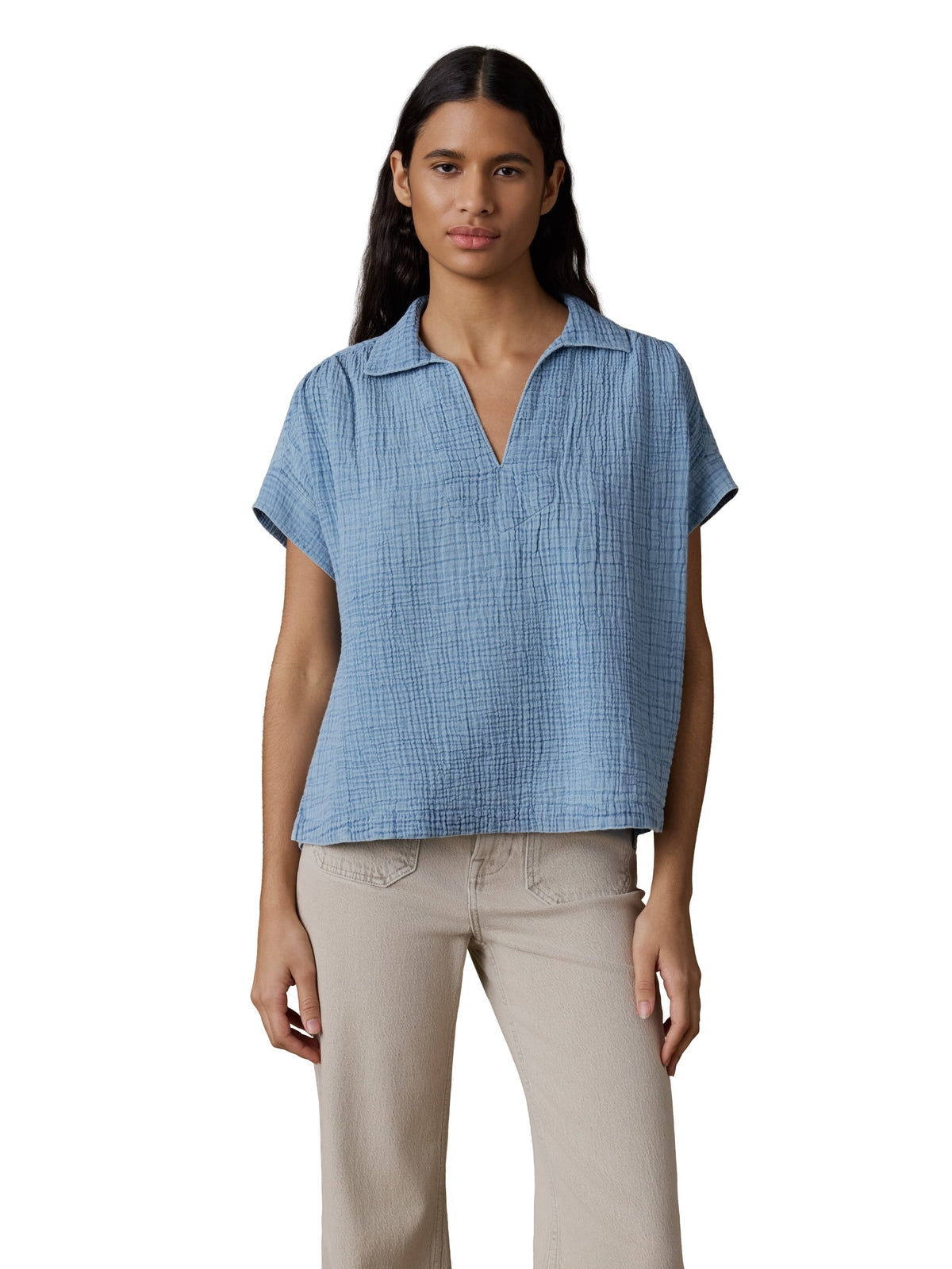 A woman wearing a blue gauze top and beige pants, image 1 of 3