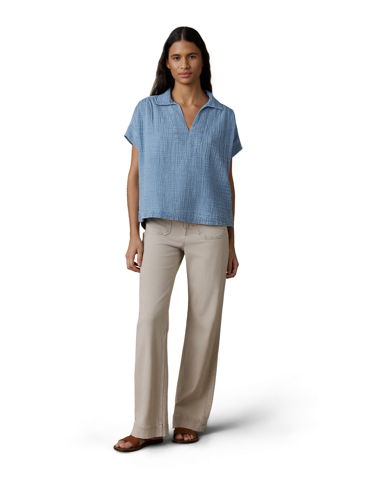 A woman wearing a blue gauze top and beige pants, image 2 of 3