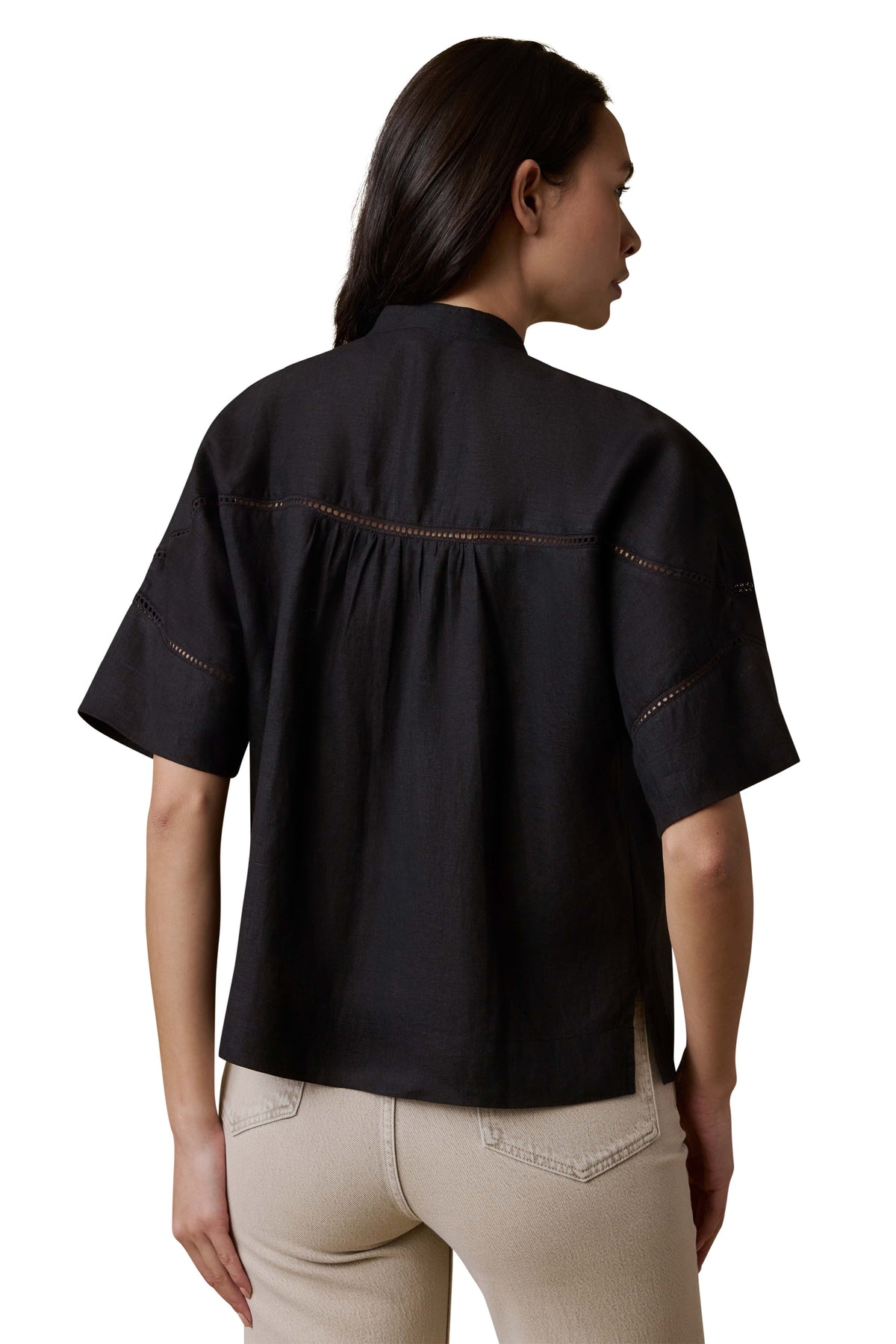A woman viewed from behind wearing a black shirt and beige pants, image 3 of 3