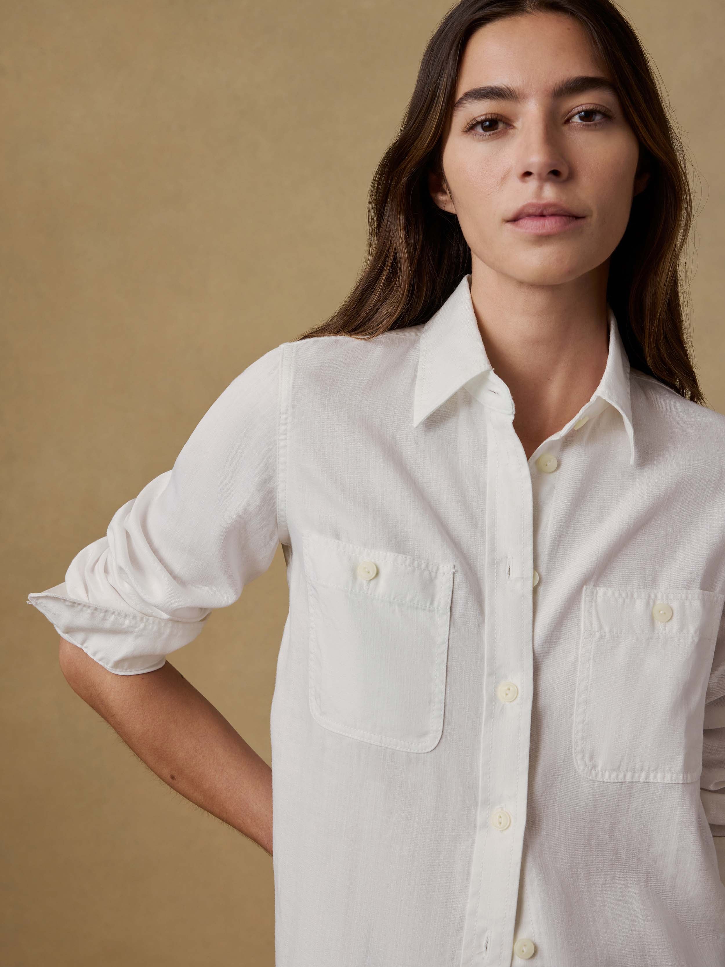 Woman wearing a white chambray shirt against a beige background
