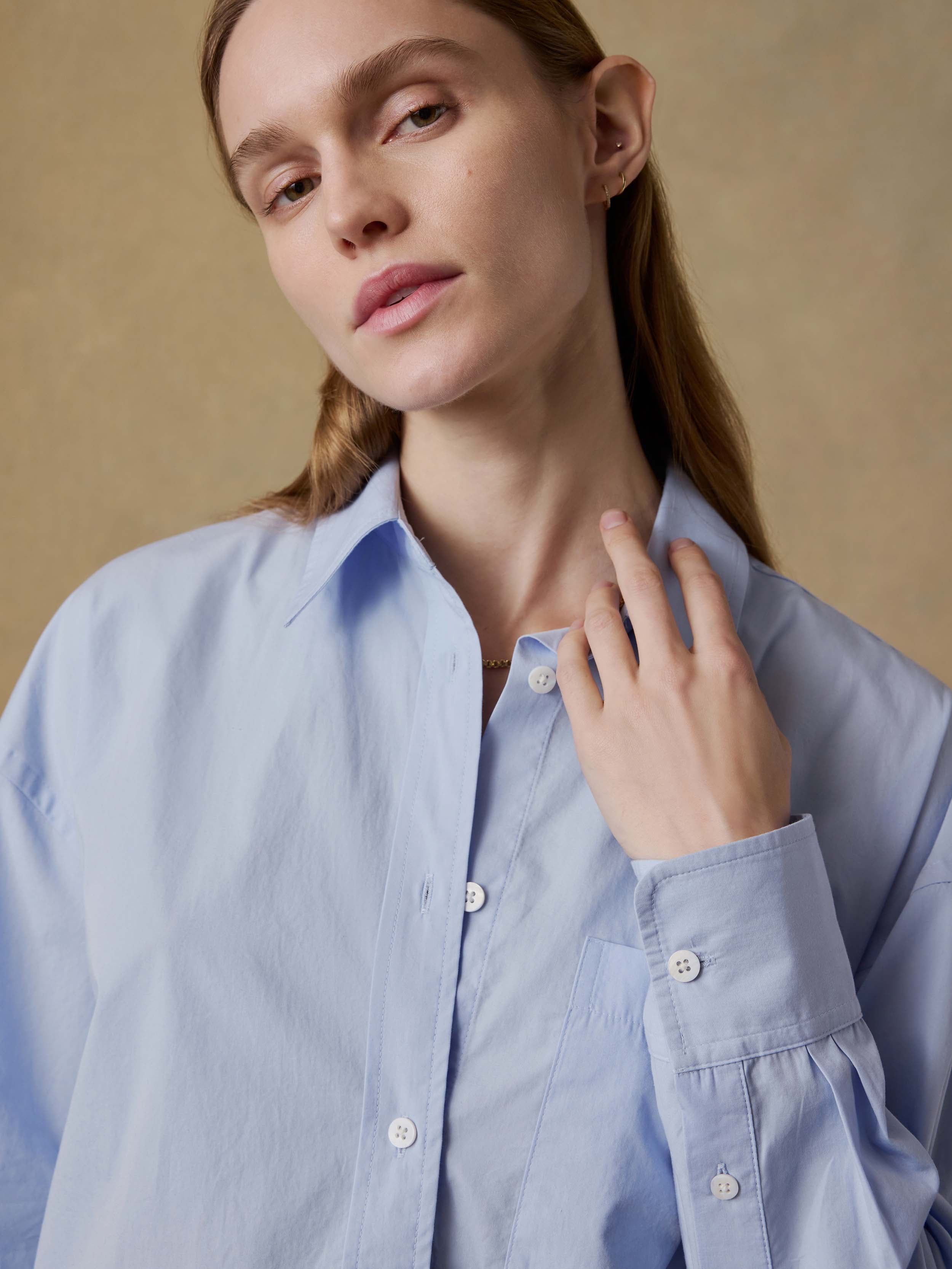 Woman wearing a light blue shirt against a beige background