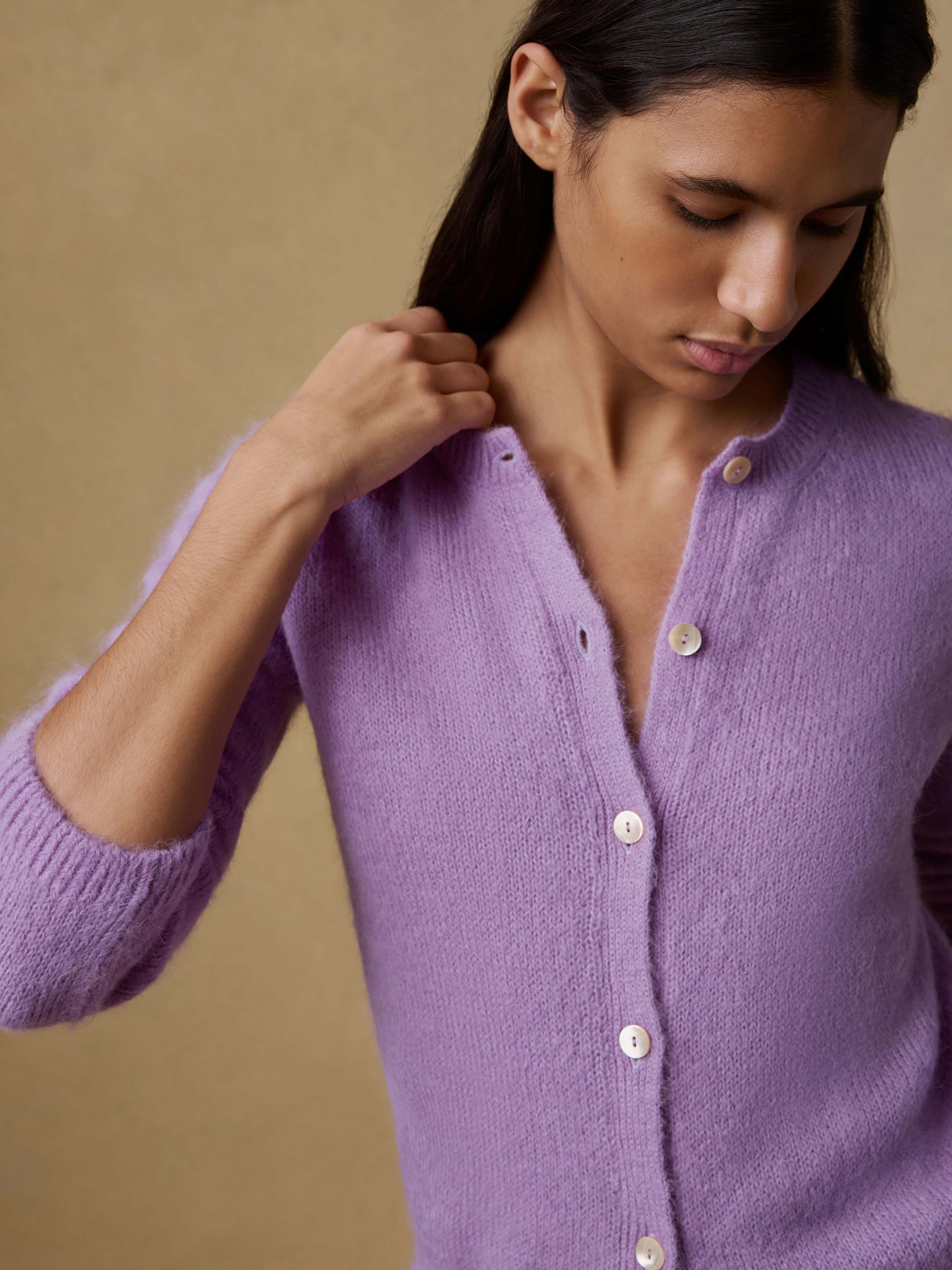Woman wearing a purple cardigan against a beige background