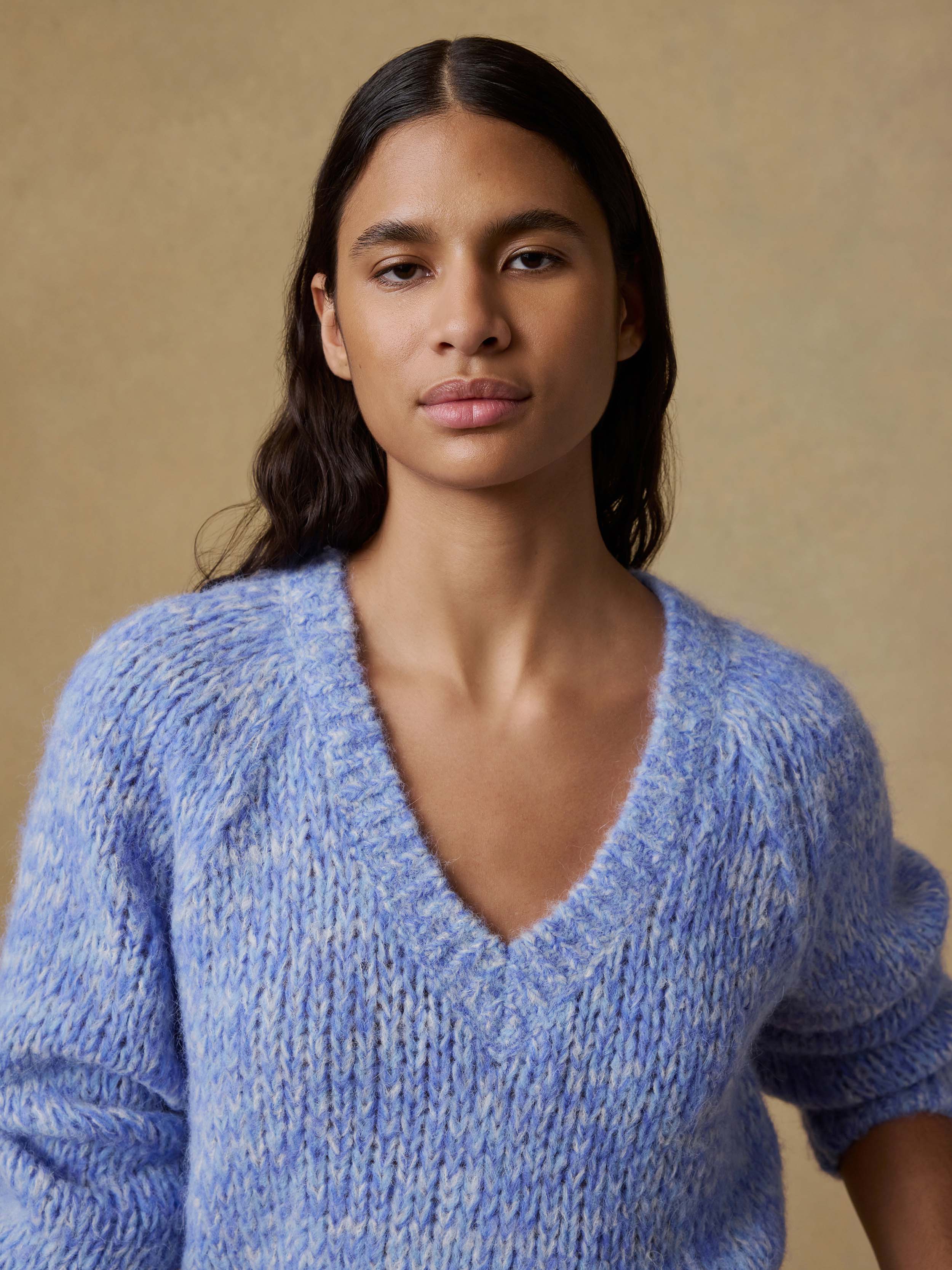 Woman wearing a blue knitted sweater against a beige background
