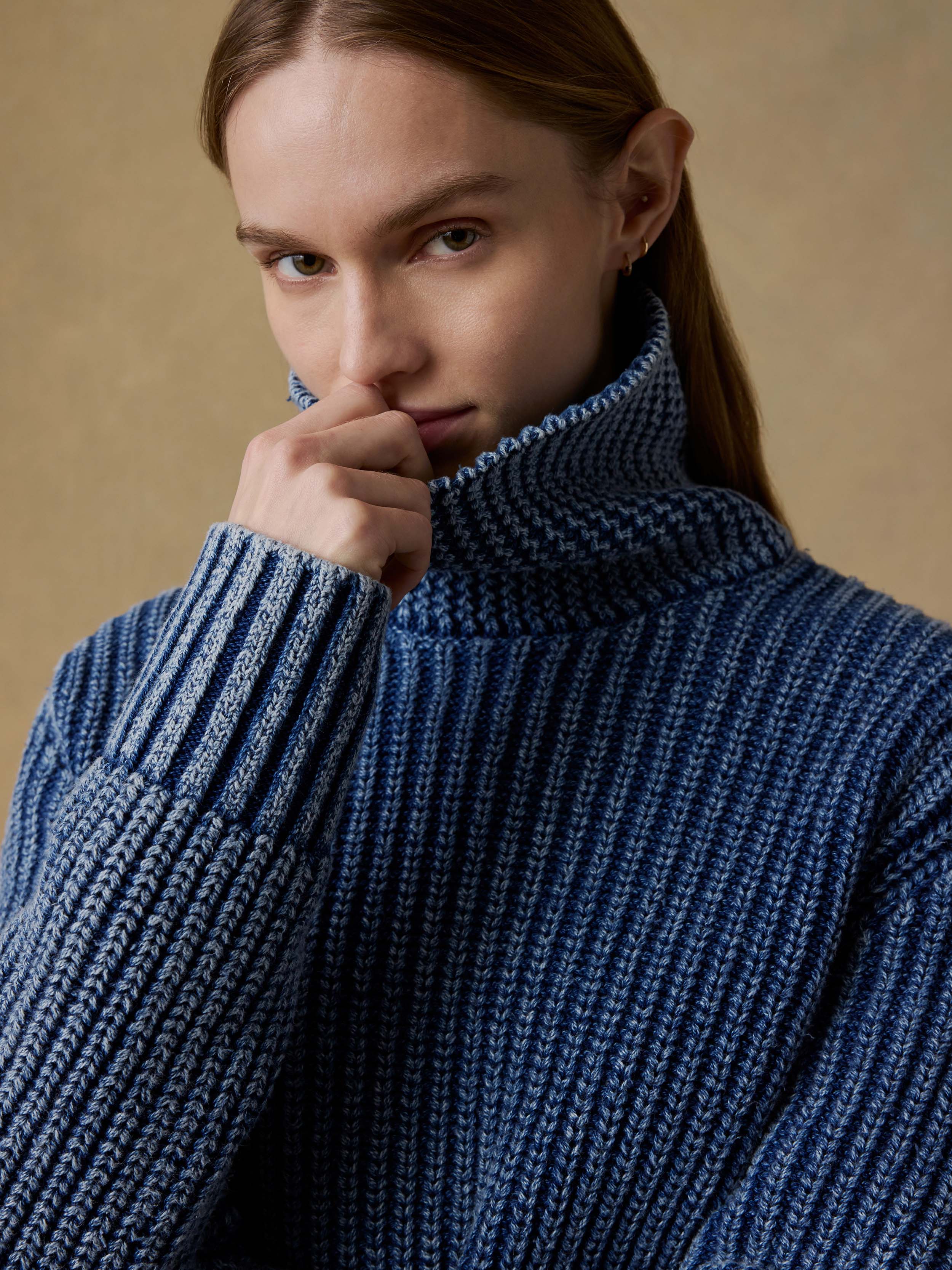 Woman wearing a blue knitted sweater against a beige background