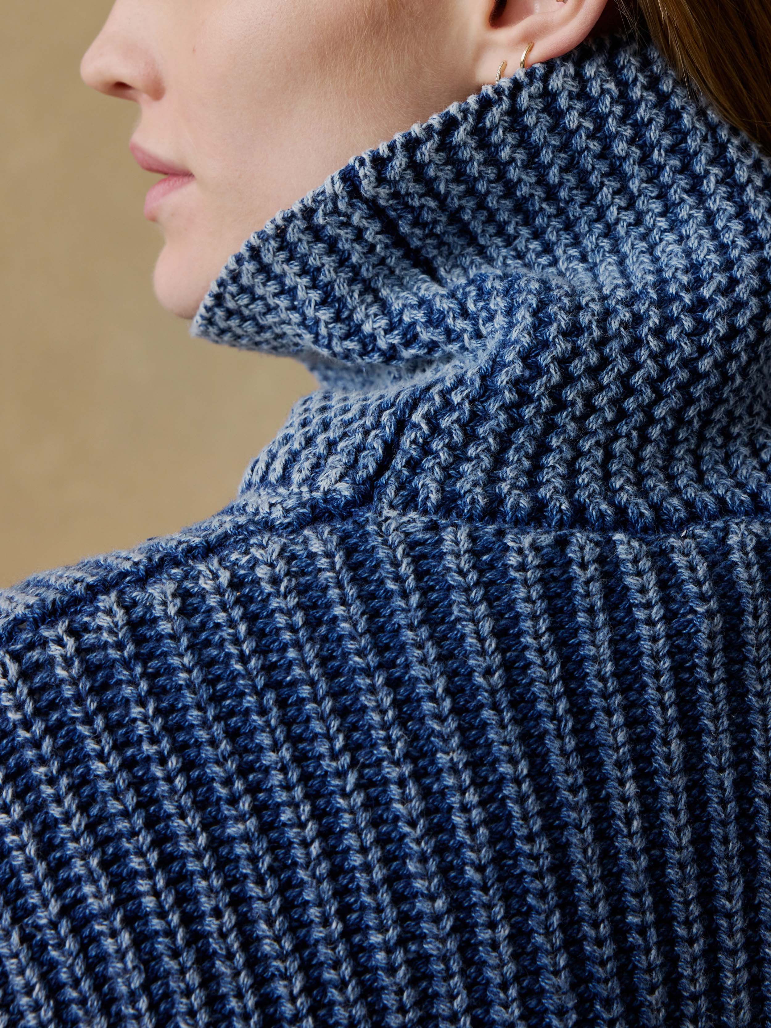 Close-up of a woman wearing a blue knitted sweater with a high collar.