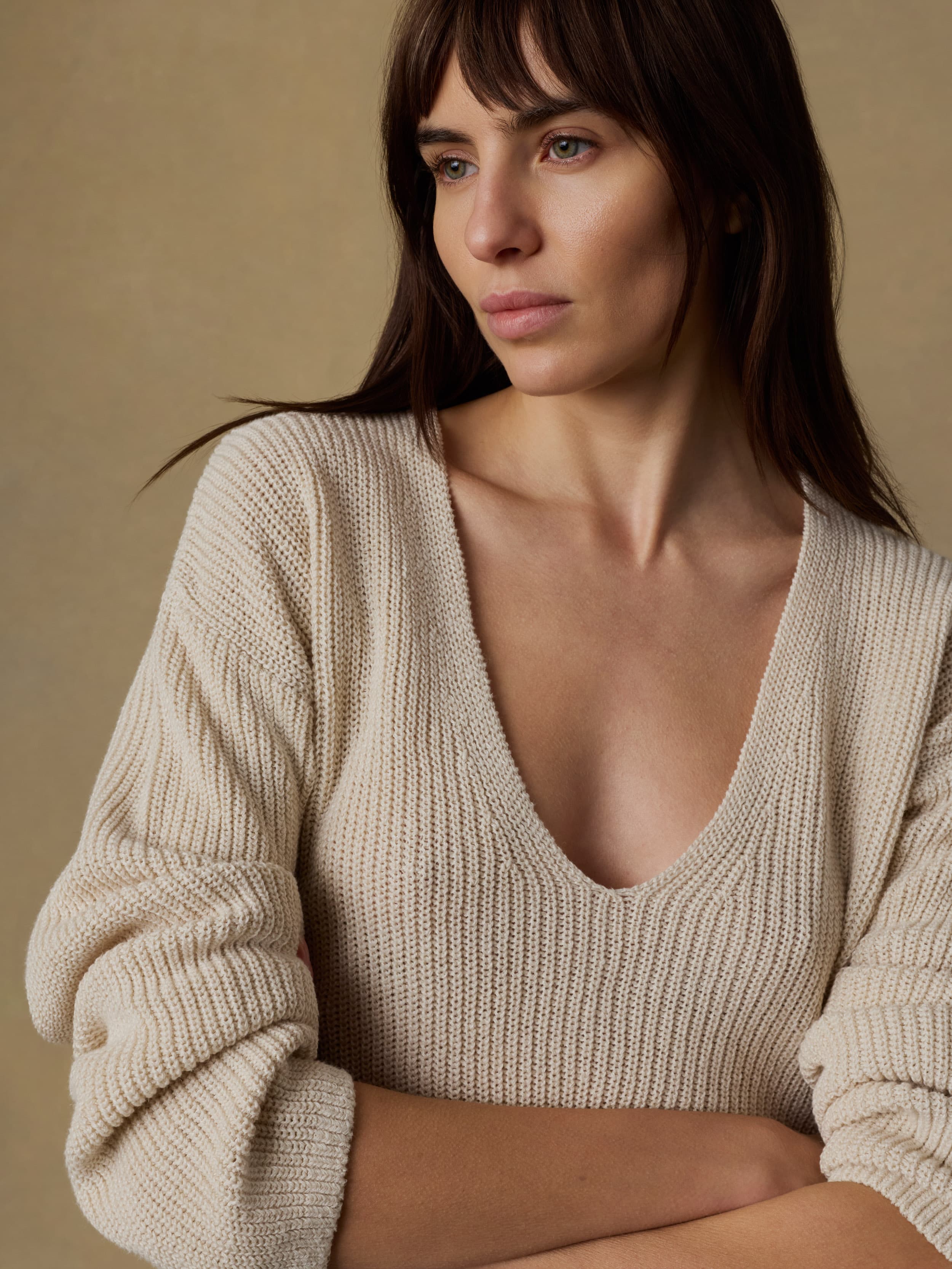 Woman wearing a beige sweater against a beige background