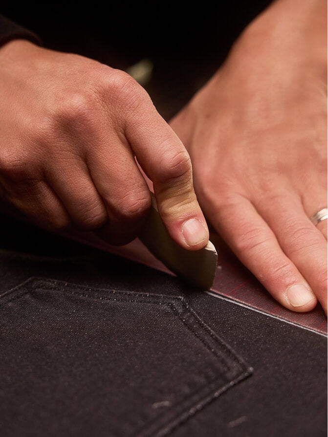 A close up shot of a fashion designer scoring stretch terry material before cutting it.