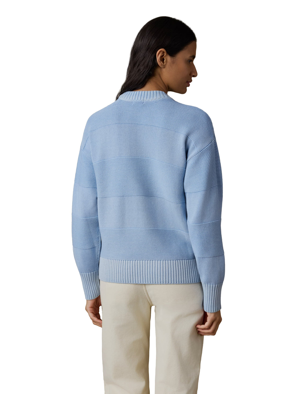 A woman viewed from behind wearing a blue sweater and white pants, image 3 of 3