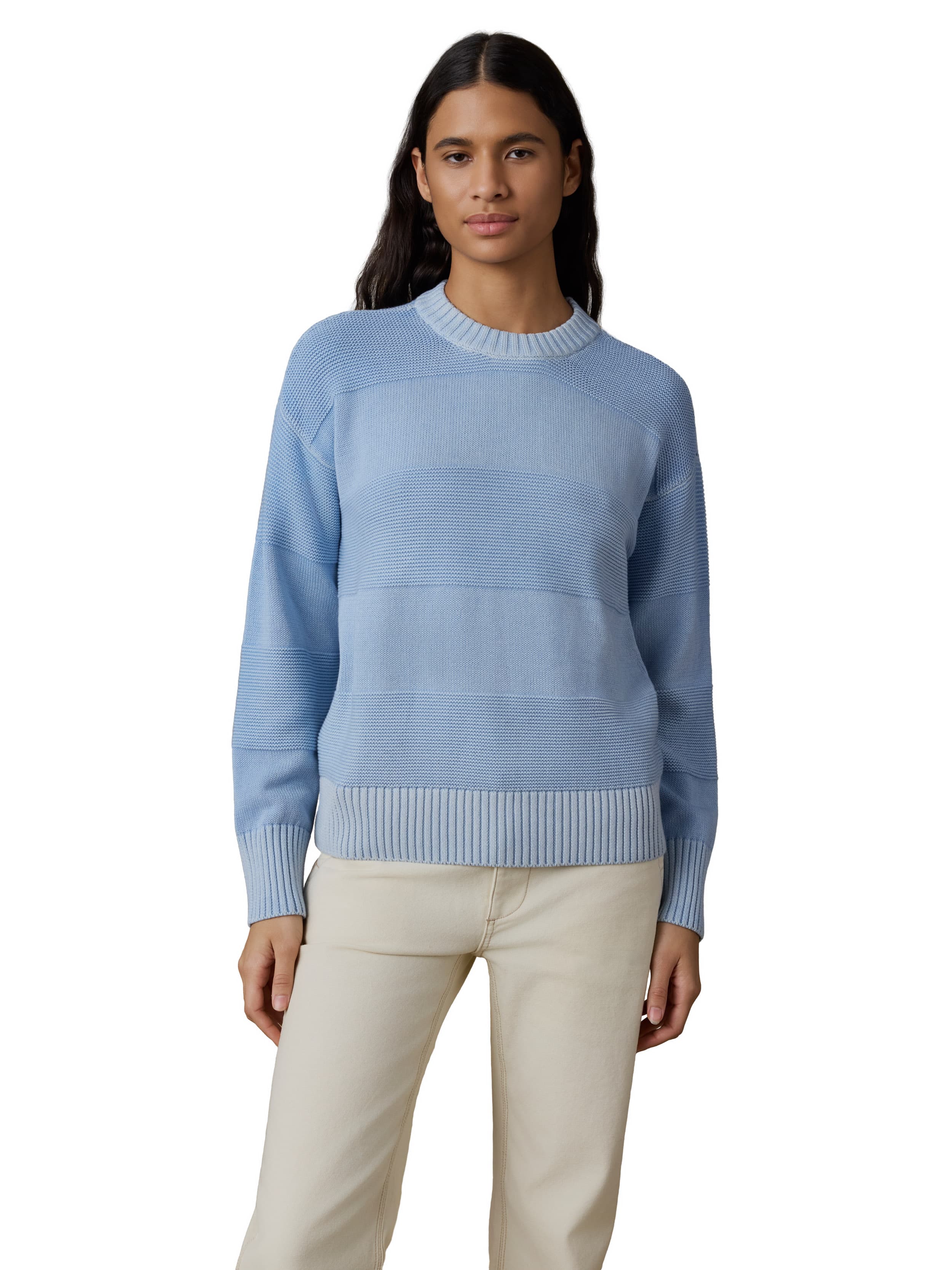 A woman wearing a blue sweater and white pants