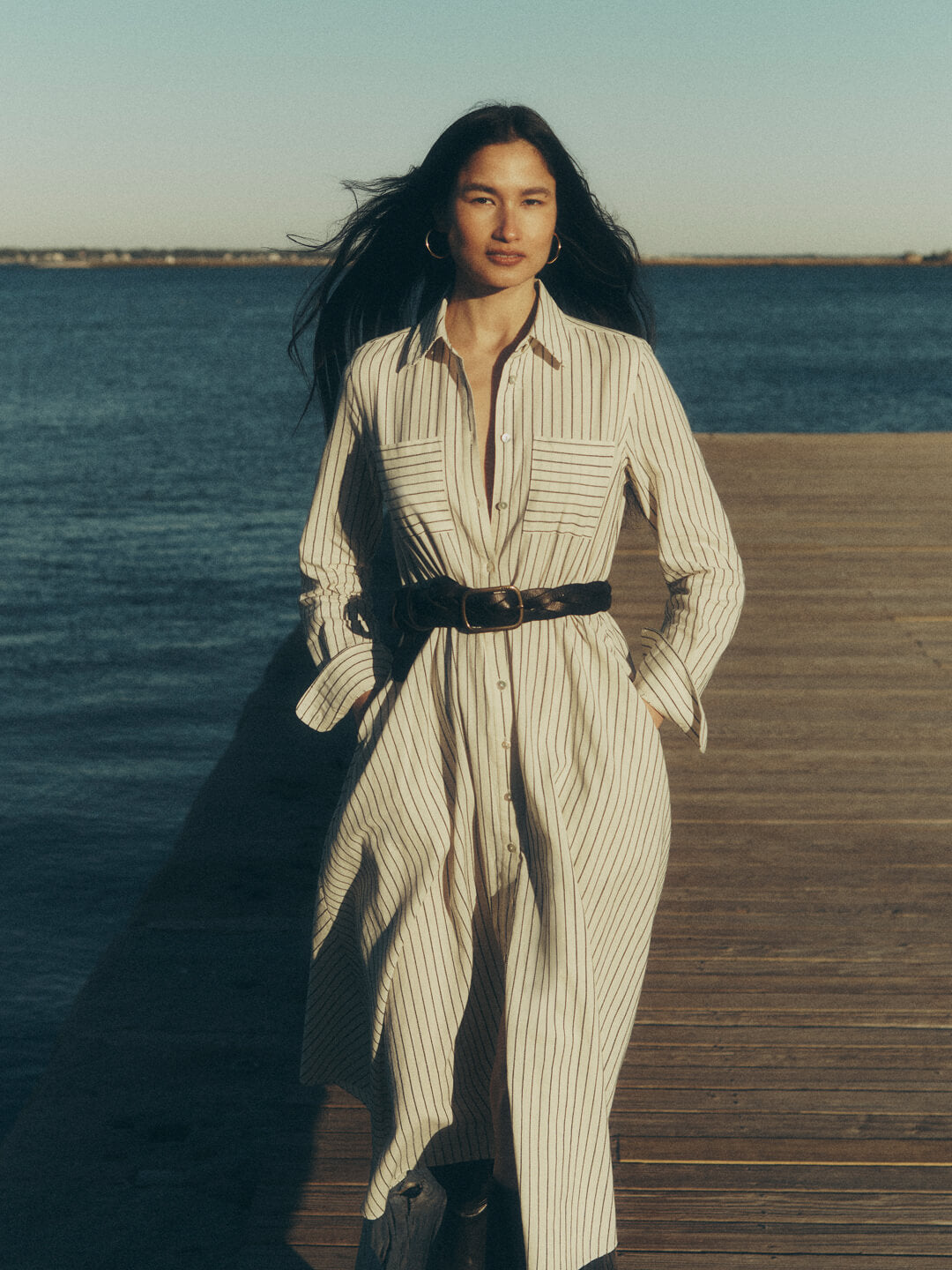 a woman on a pier wearing a striped shirt dress