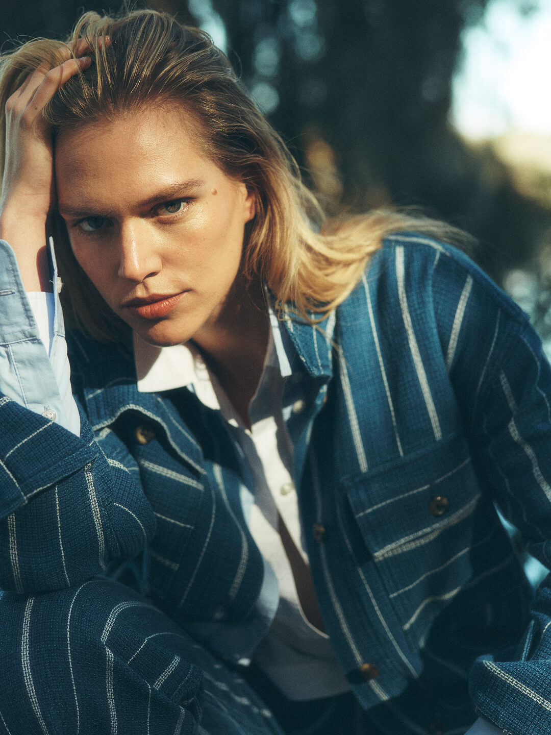 female model in southern low country landscape surrounded by a pond and Spanish moss, wearing a indigo striped jacket and pants, paired with a chambray shirt 