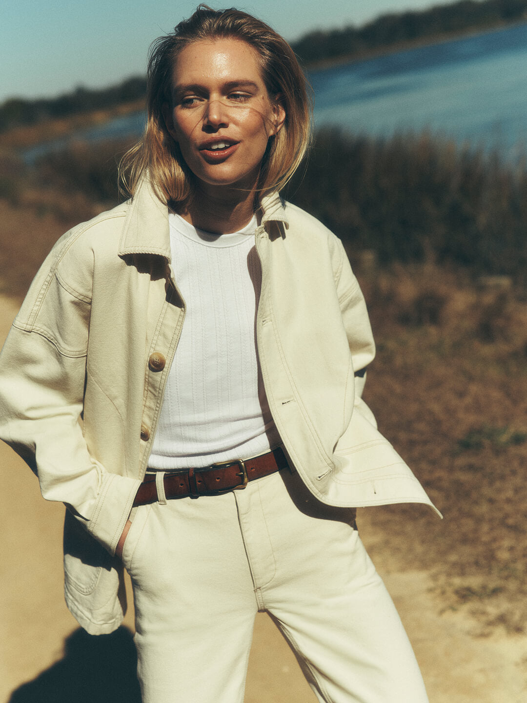 Female model on a low country bay wearing a sunwashed canvas barn jacket and pants paired with a cotton tank.