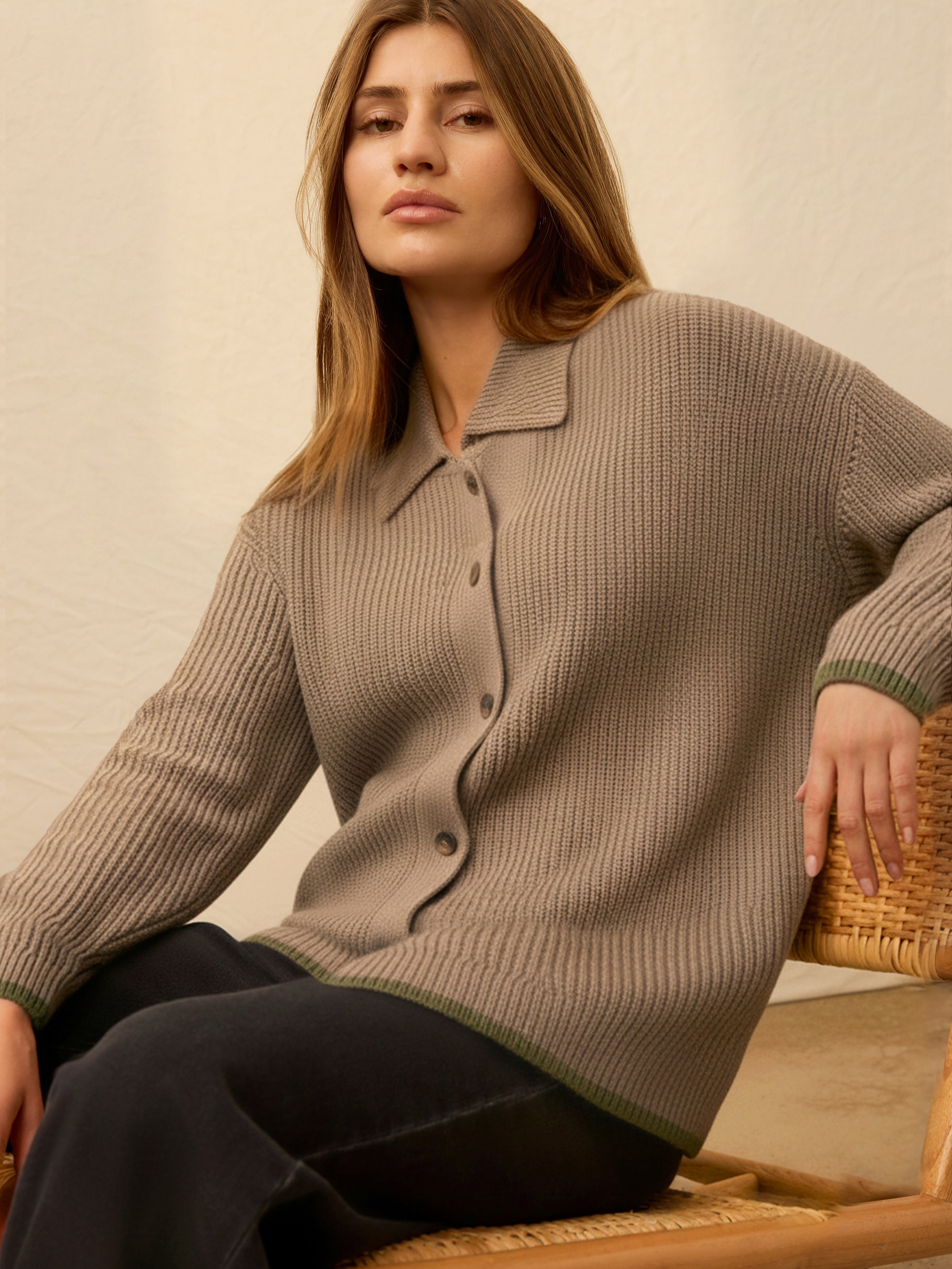 Woman wearing a brown knitted cardigan against a beige background