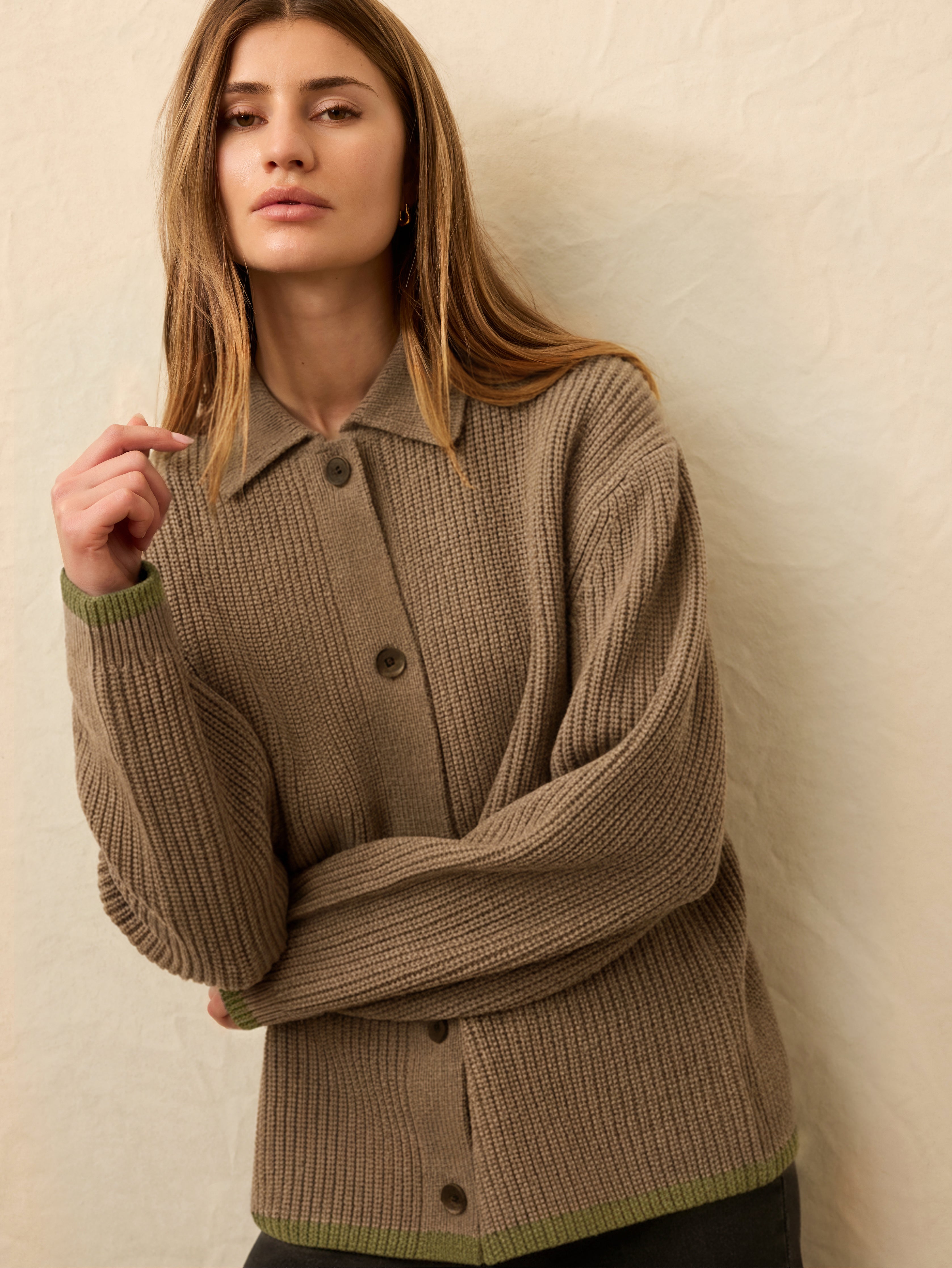Woman wearing a brown knitted cardigan against a beige background